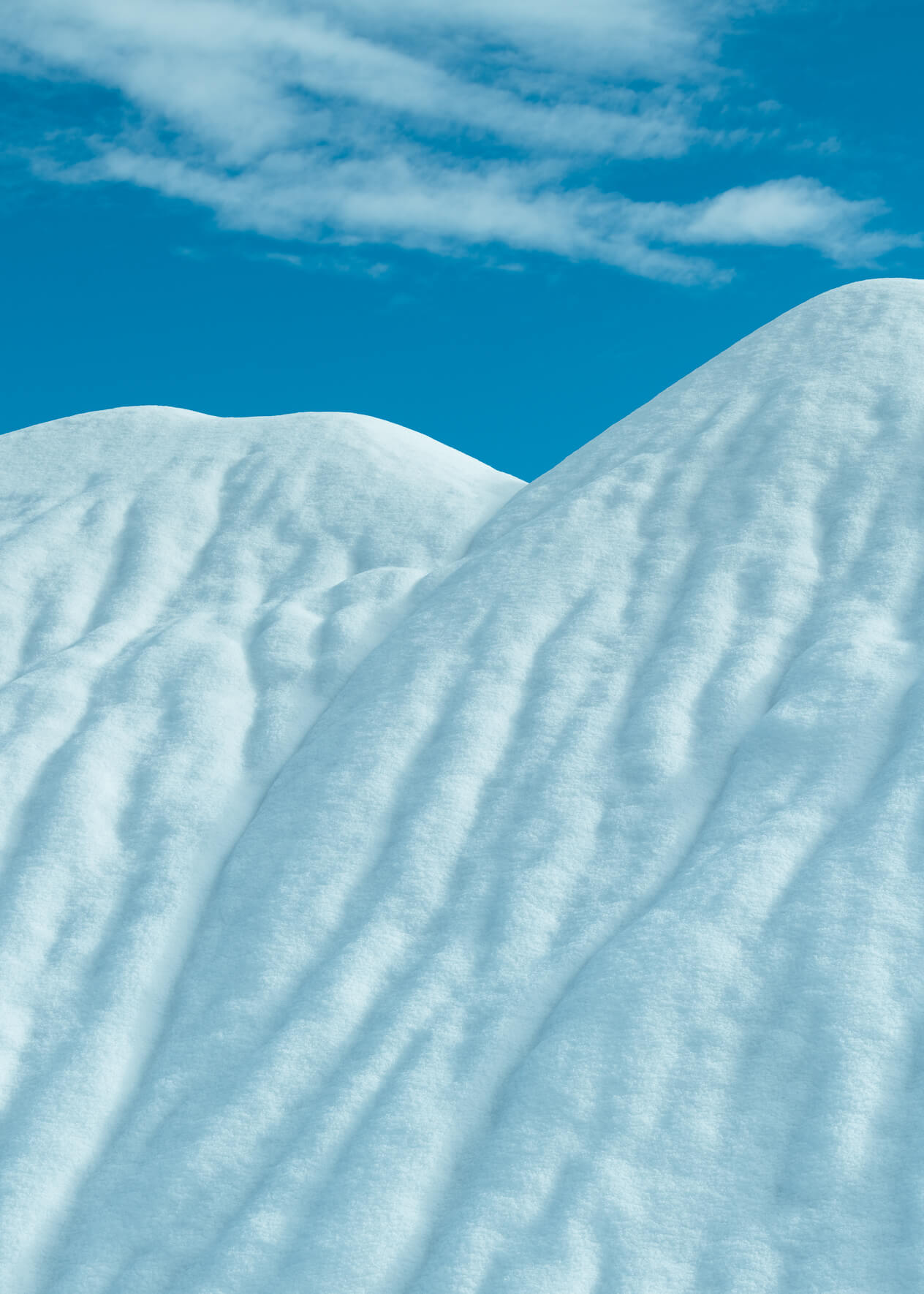 Abstract winter landscape with snow covered hills and a blue sky with clouds