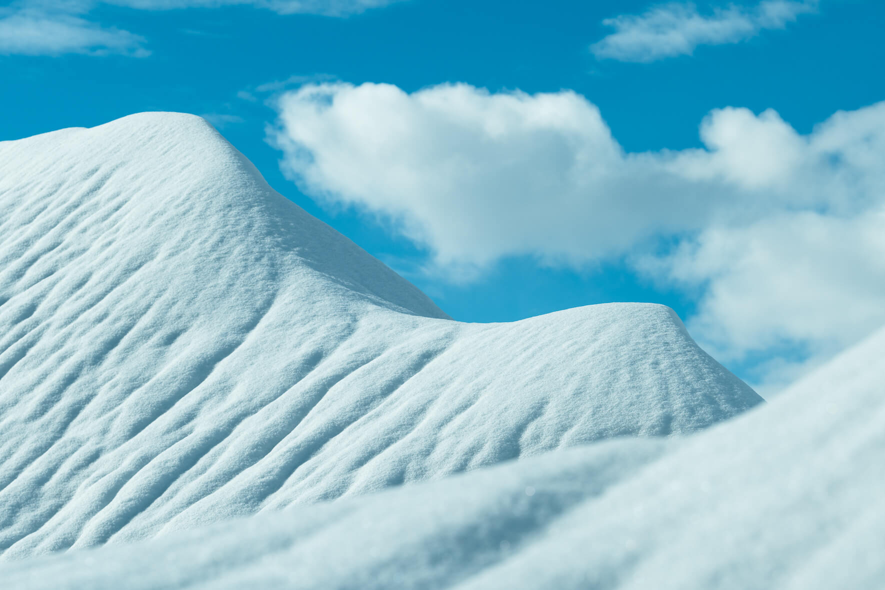 Abstract winter landscape with snow covered hills and a blue sky with soft clouds