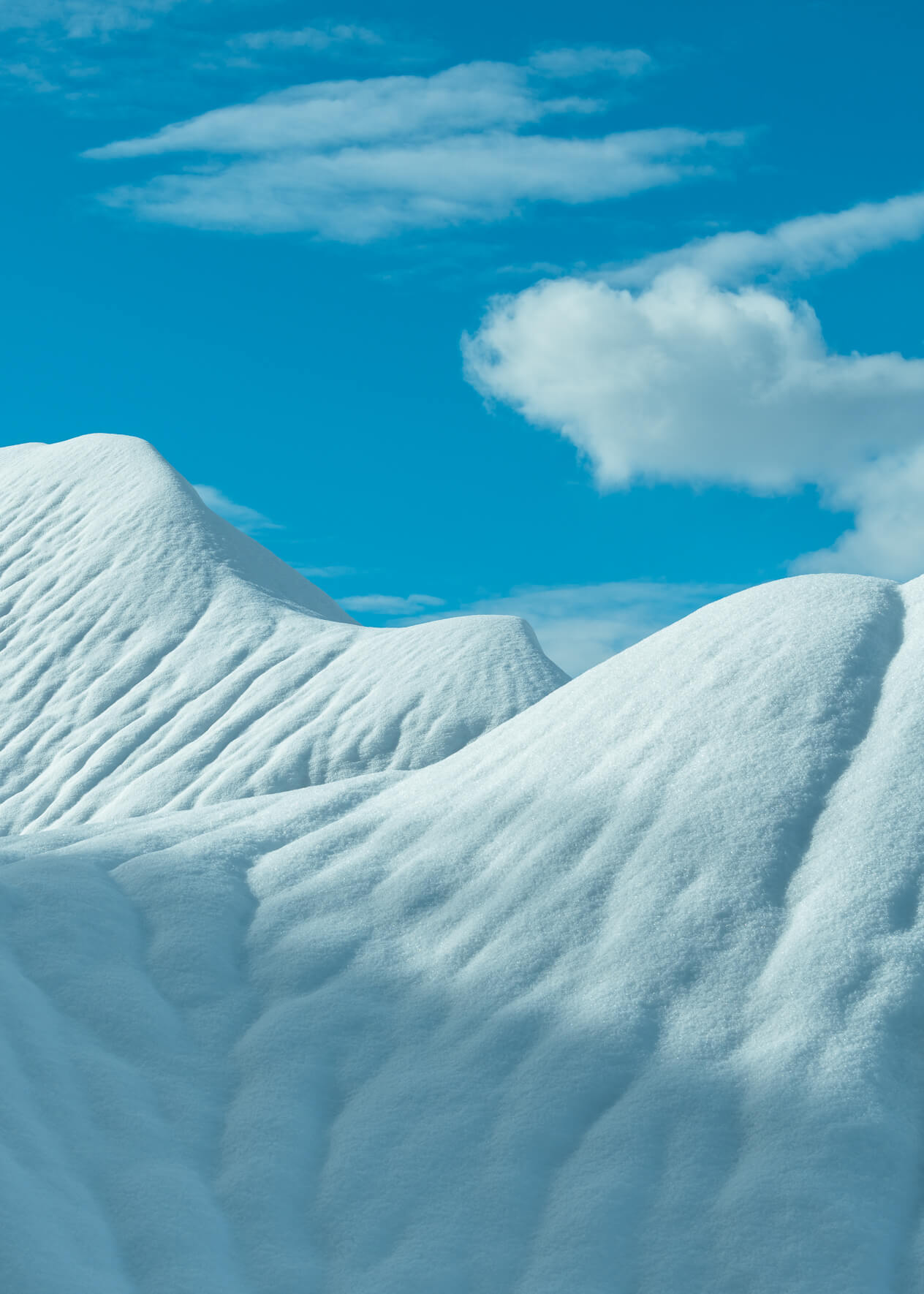 Winter landscape with snow covered hills and a blue sky with clouds