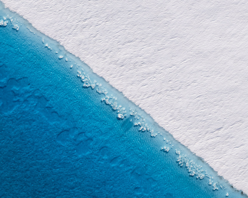 Deep blue meltwater lake with ice floes on Columbia Glacier, captured from an aerial perspective