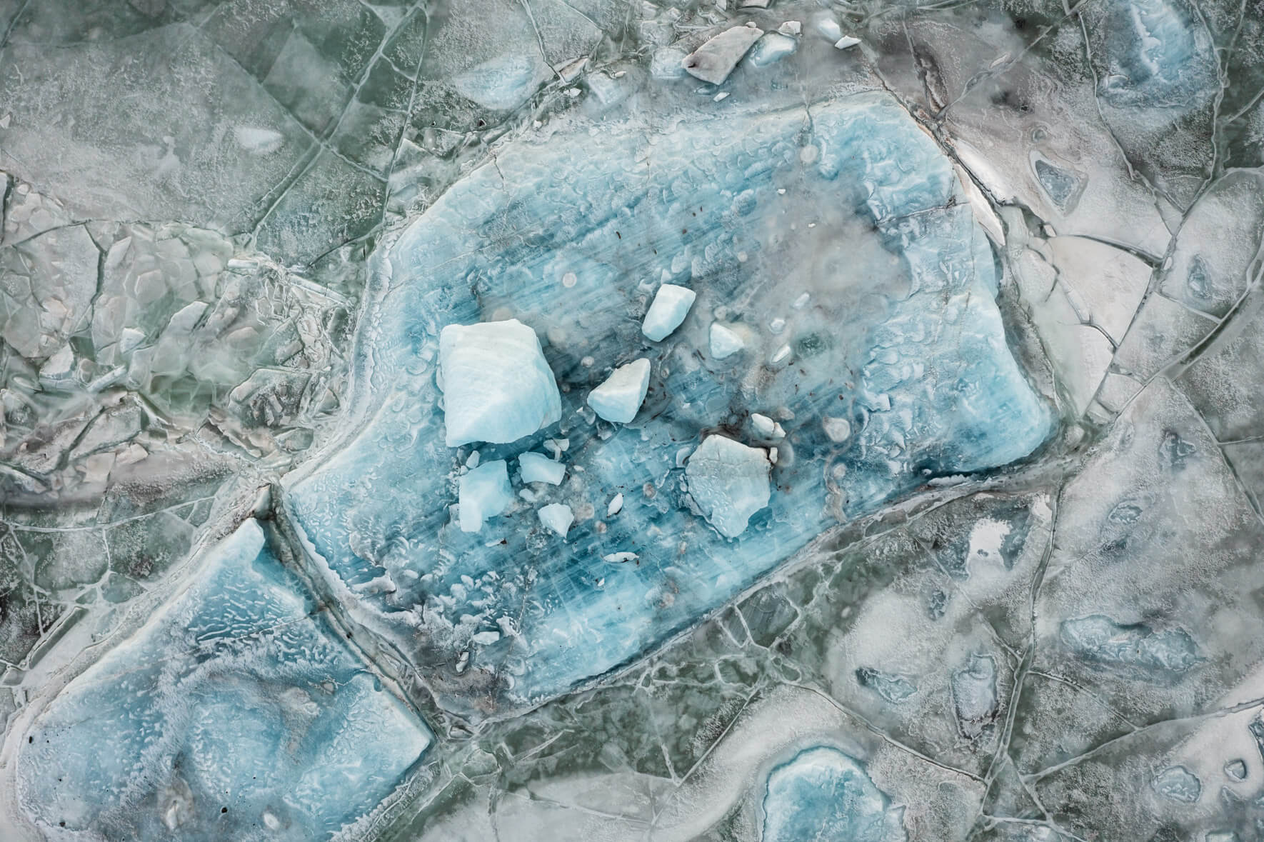 Iceland’s Svínafellslón lagoon from above, revealing deep fissures in the frozen surface and icebergs