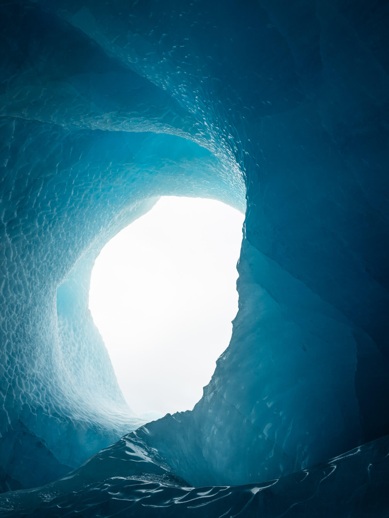 Exploring a surreal ice cave inside an iceberg, where walls glow in shades of blue