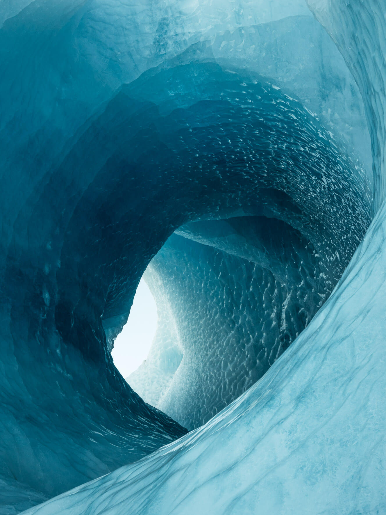 Massice ice tunnel inside an iceberg in Iceland, surrounded by deep blue glacial ice