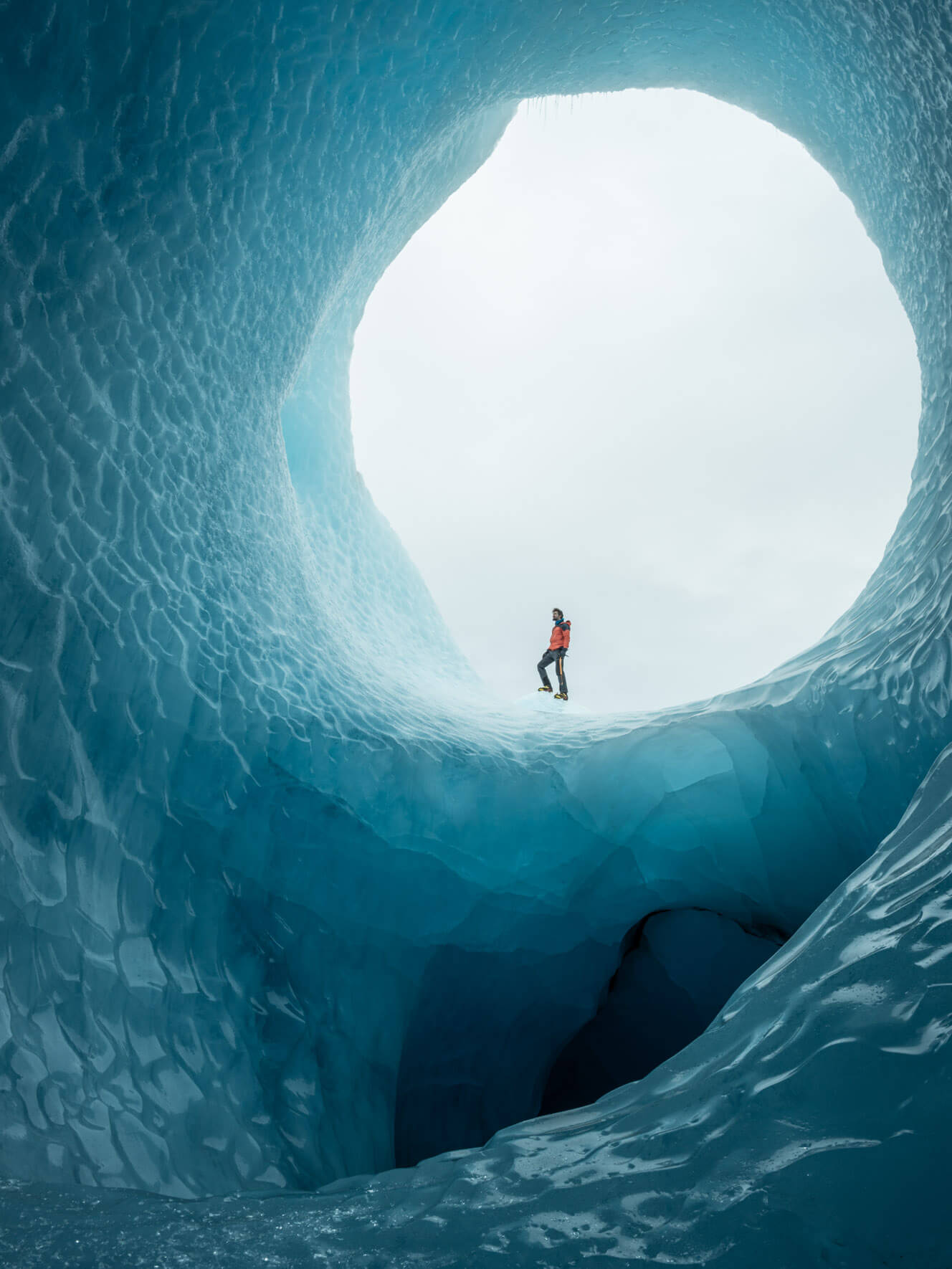 Man standing in massice ice tunnel inside an iceberg in Iceland