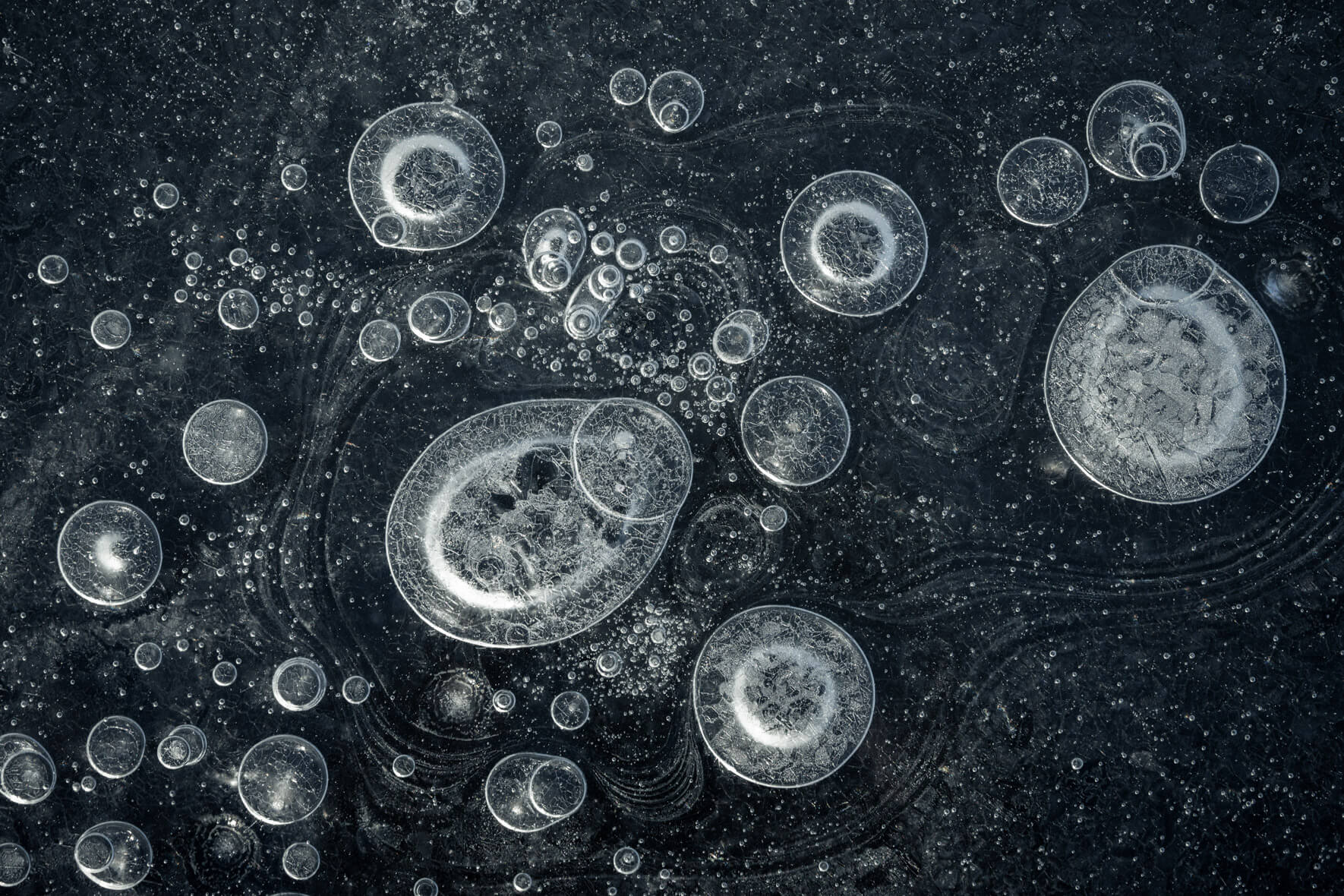 Macro photography of air bubbles trapped in the dark ice of a glacier lagoon