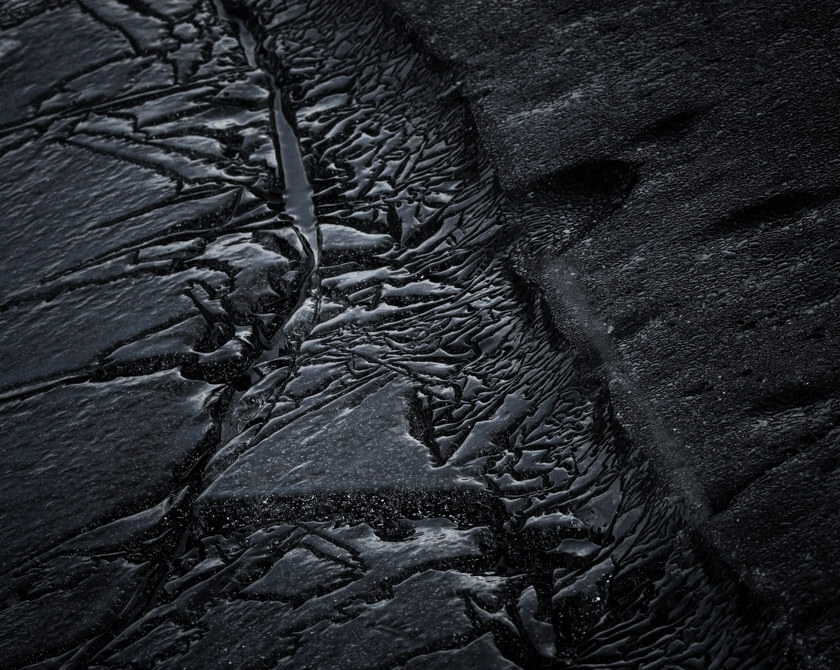 Cracked dark ice on the shores of Lake Kleifarvatn, forming striking natural patterns in Iceland
