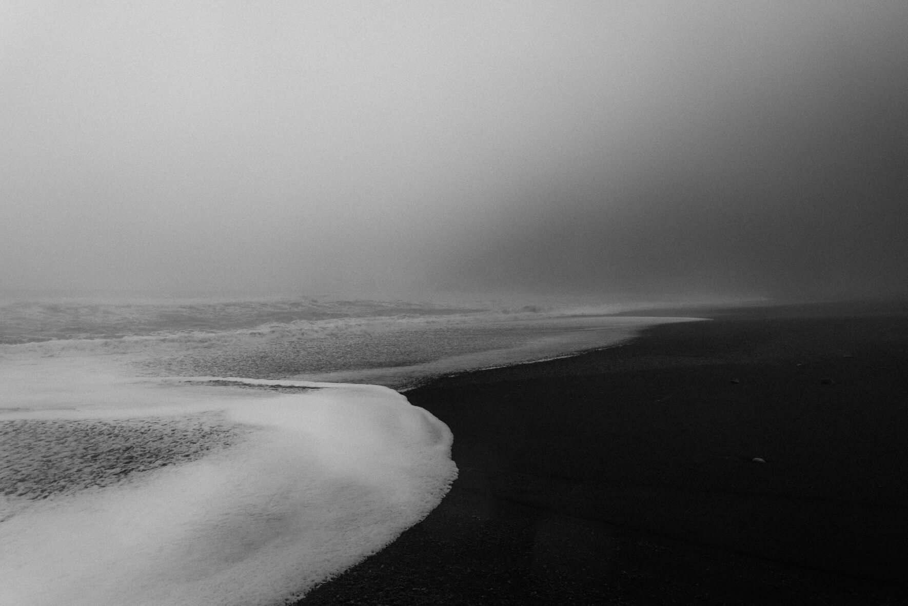 Waves on the black sand beach of Vík n Iceland on a foggy day (black & white)