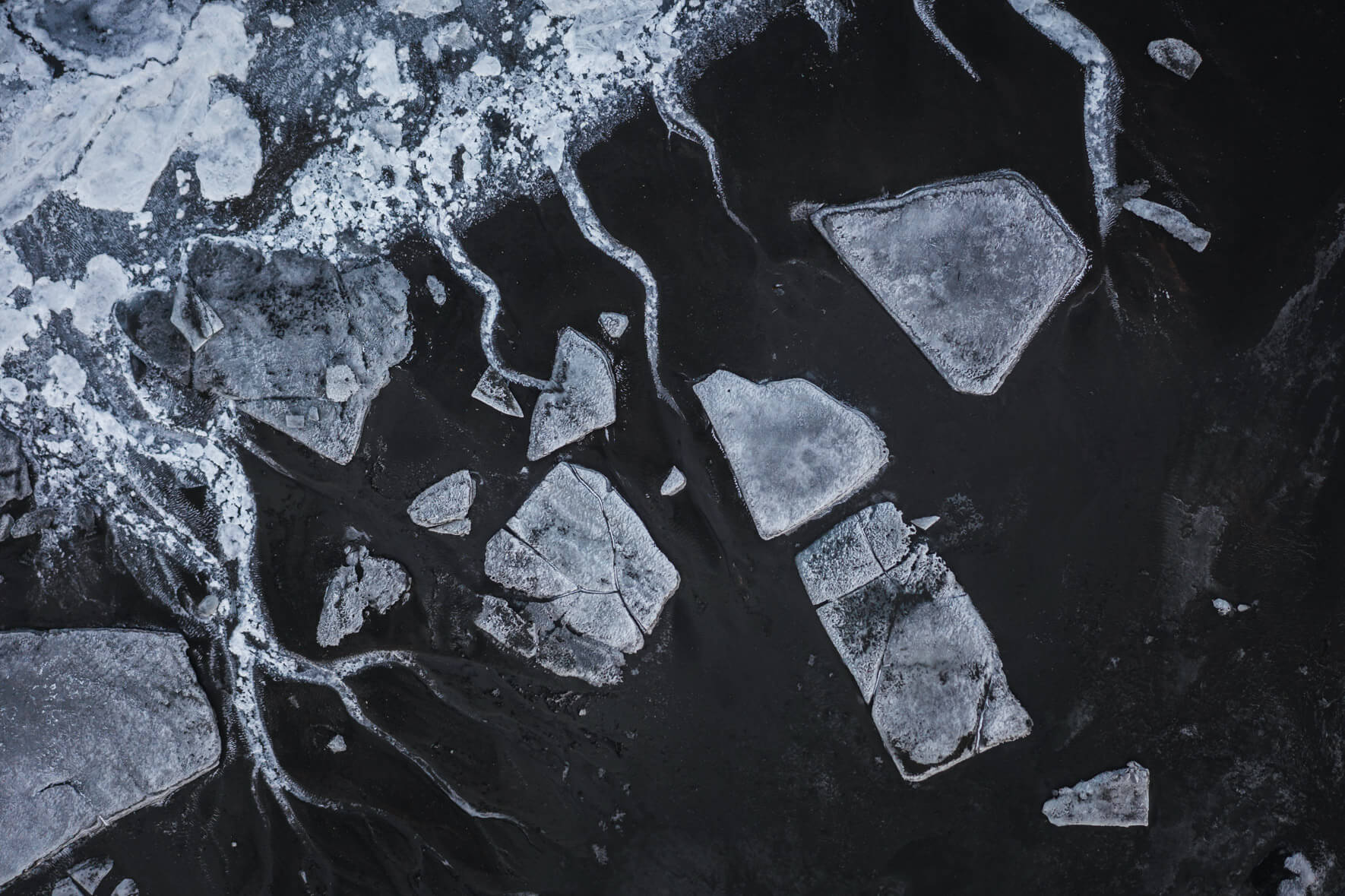 Aerial view of a dried glacier riverbed in Iceland with snow ice and exposed sediment