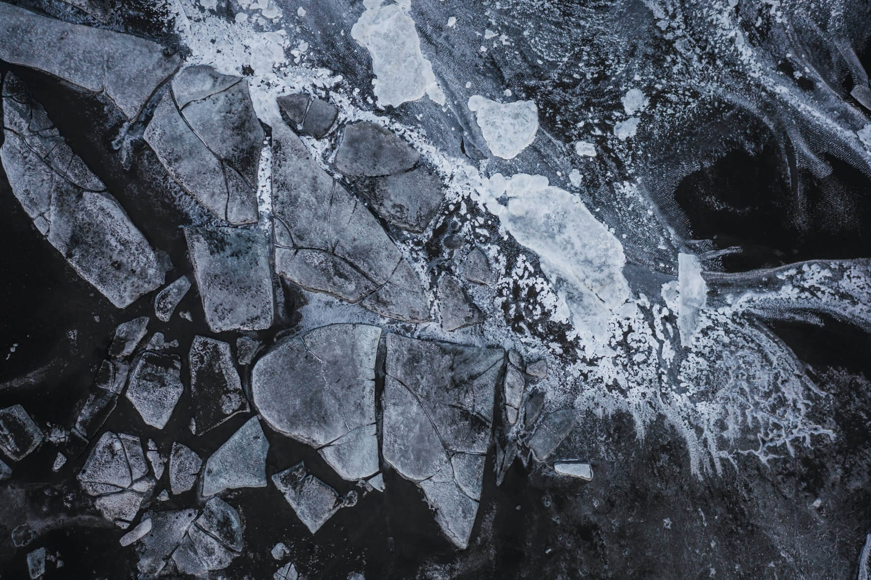 Monochrome aerial shot of Iceland’s frozen riverbed with snow and ice