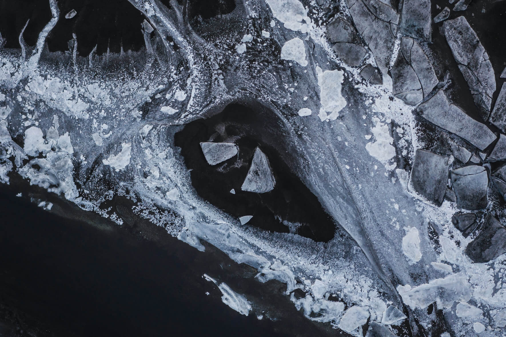 Drone perspective of Iceland’s winter riverbed where snow and ice meet dark sediment