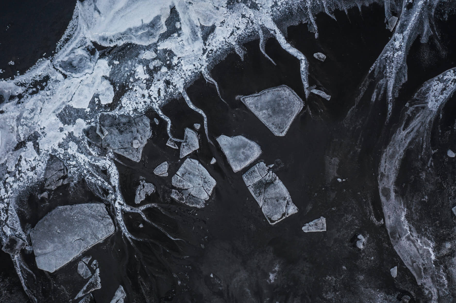 Monochrome aerial shot of Iceland’s frozen riverbed showcasing winter textures and patterns