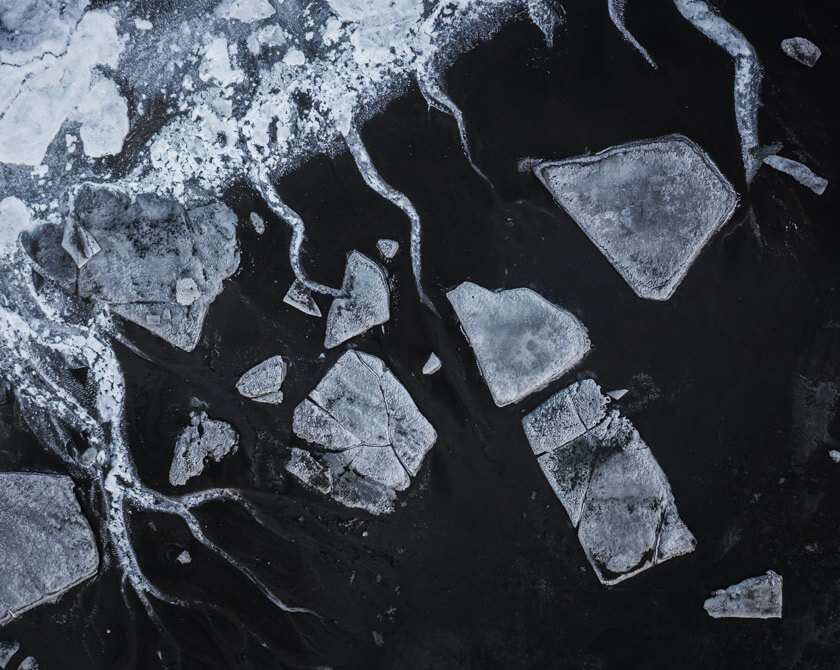 Monochrome aerial shot of Iceland’s frozen riverbed with ice and snow