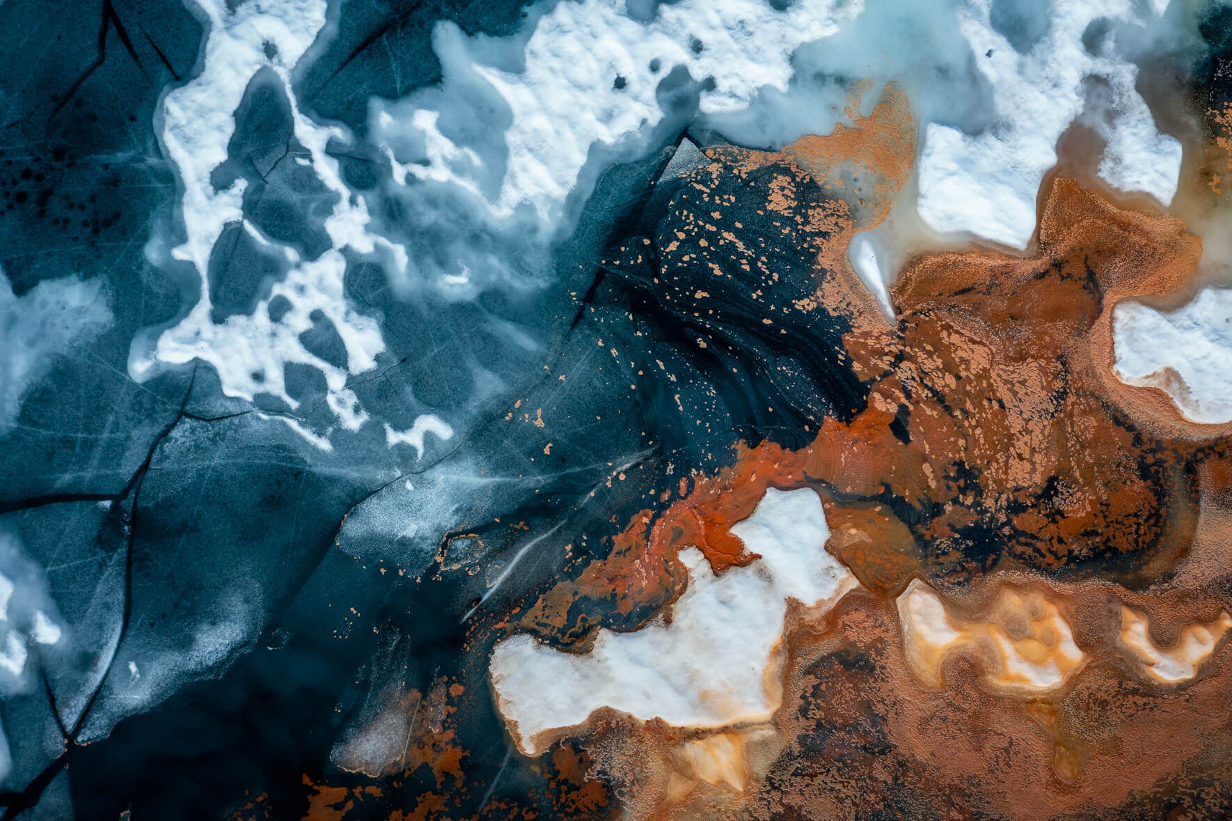 Abstract aerial view of a thawing lake in Norway with cracked ice surface and remnants of snow as well as red pollen