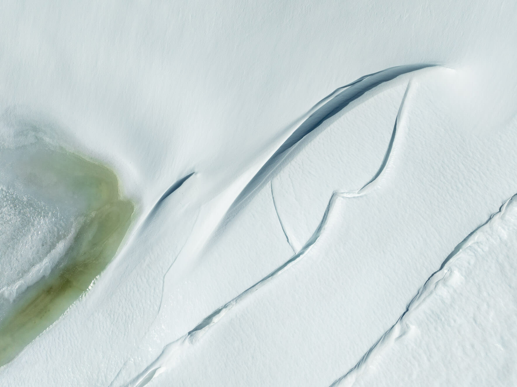 Aerial perspective of snow-covered ice with deep cracks on Hardangervidda’s frozen plateau