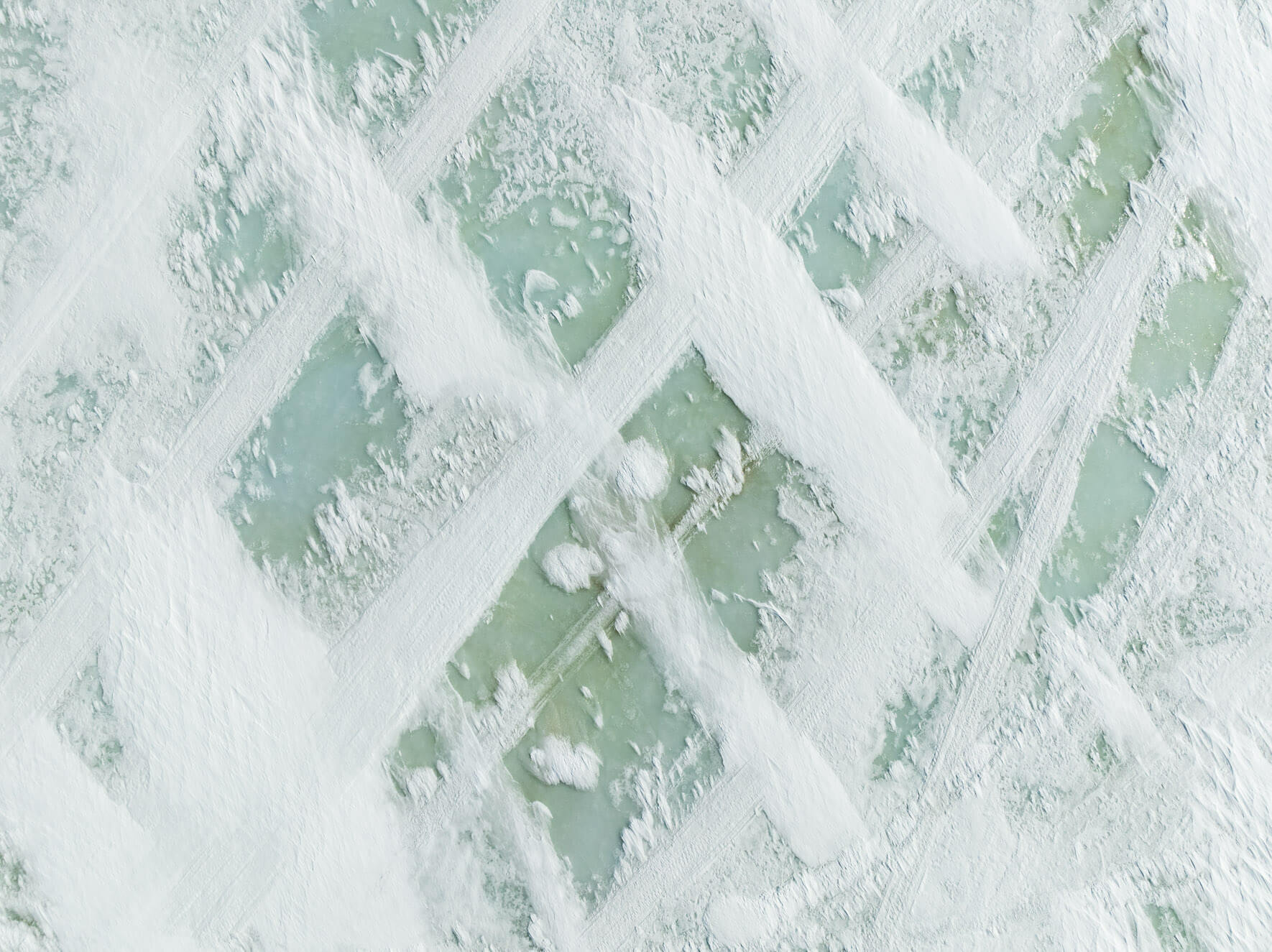 Drone image of turquoise ice emerging through snow-covered surfaces in Hardangervidda Norway