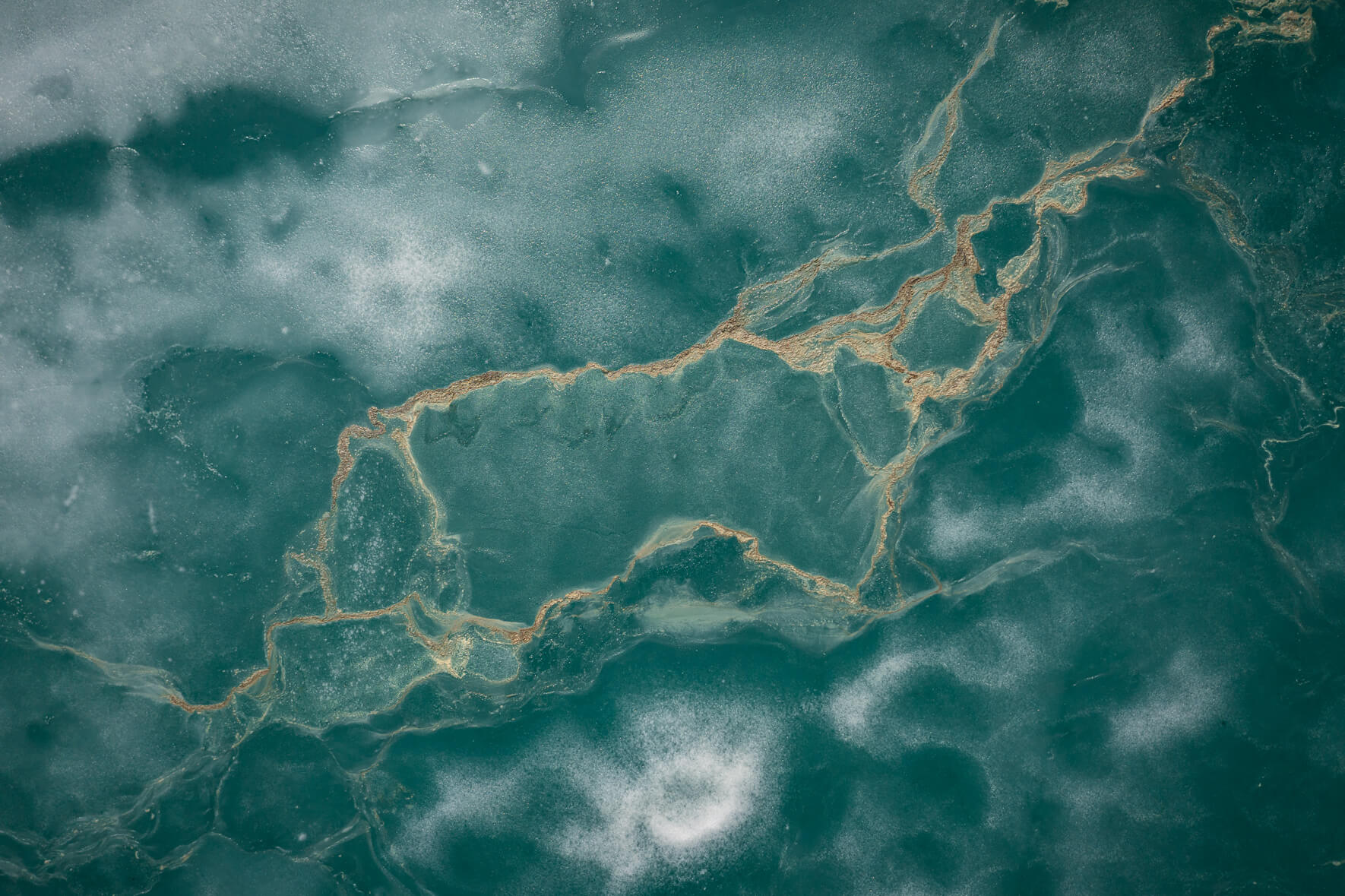 Abstract aerial view of a thawing lake in Norway with remnants of ice and snow and flower pollen