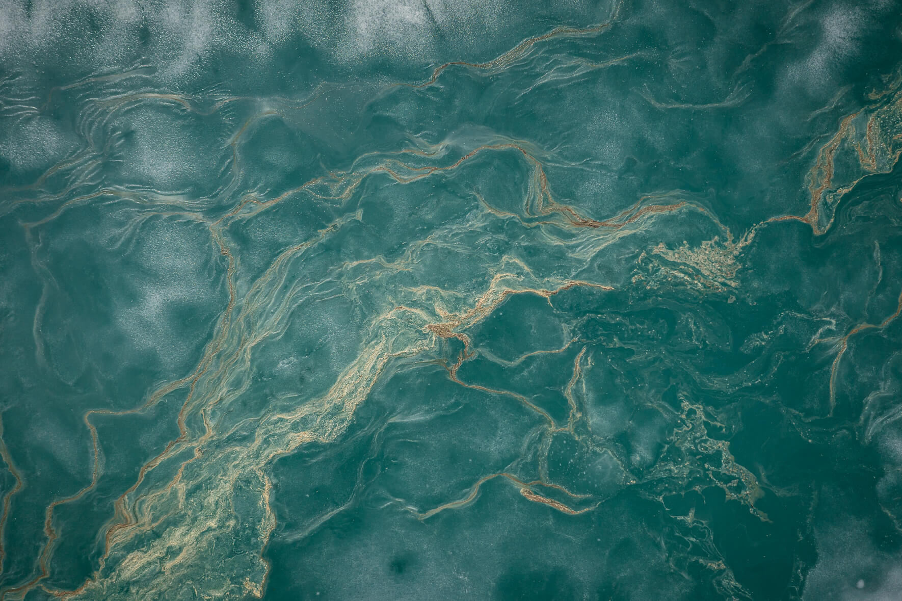 Aerial view of a thawing lake in Norway with remnants of ice and flower pollen