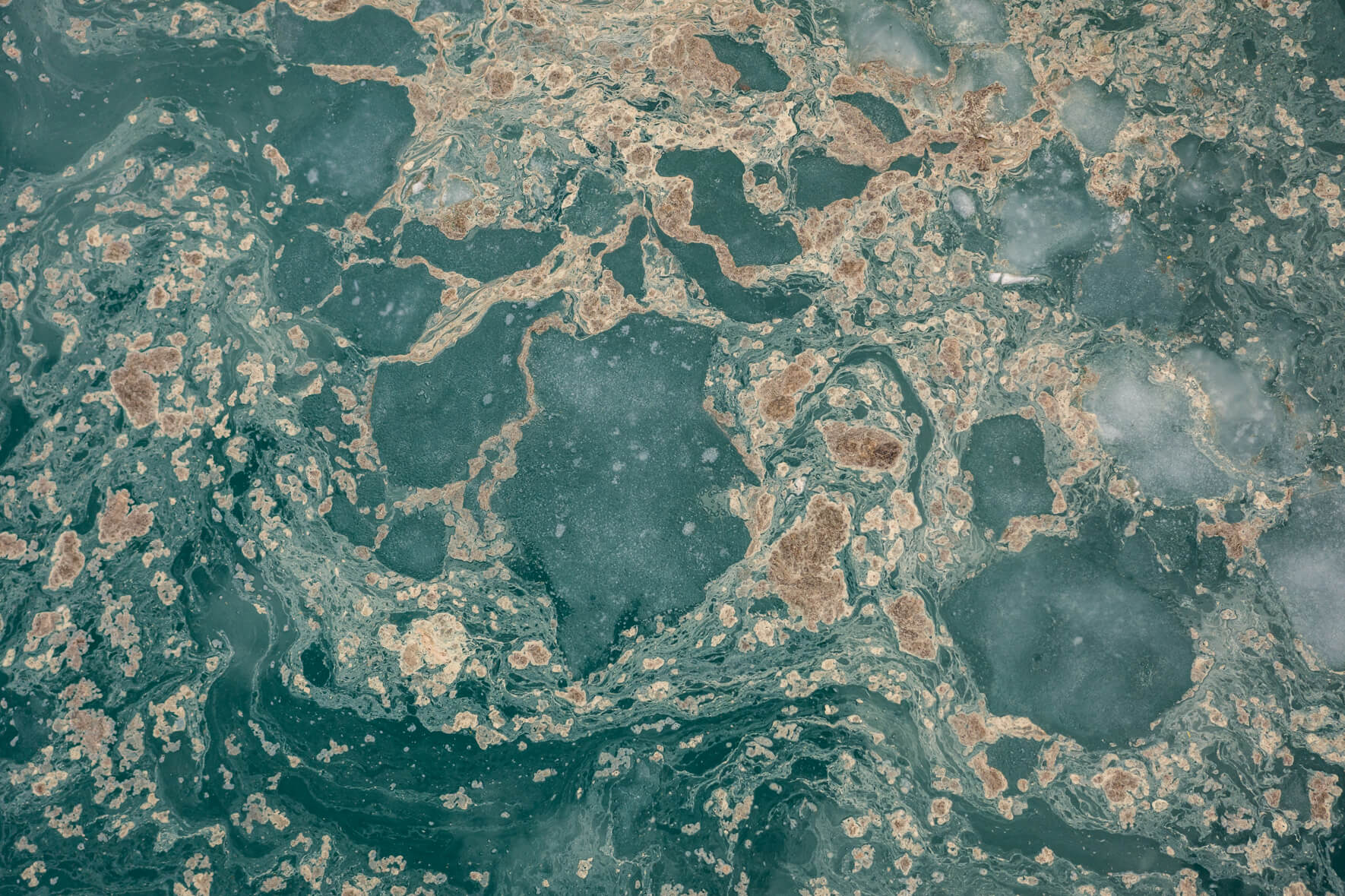 Abstract aerial view of a thawing lake with flower pollen forming streaks on the water