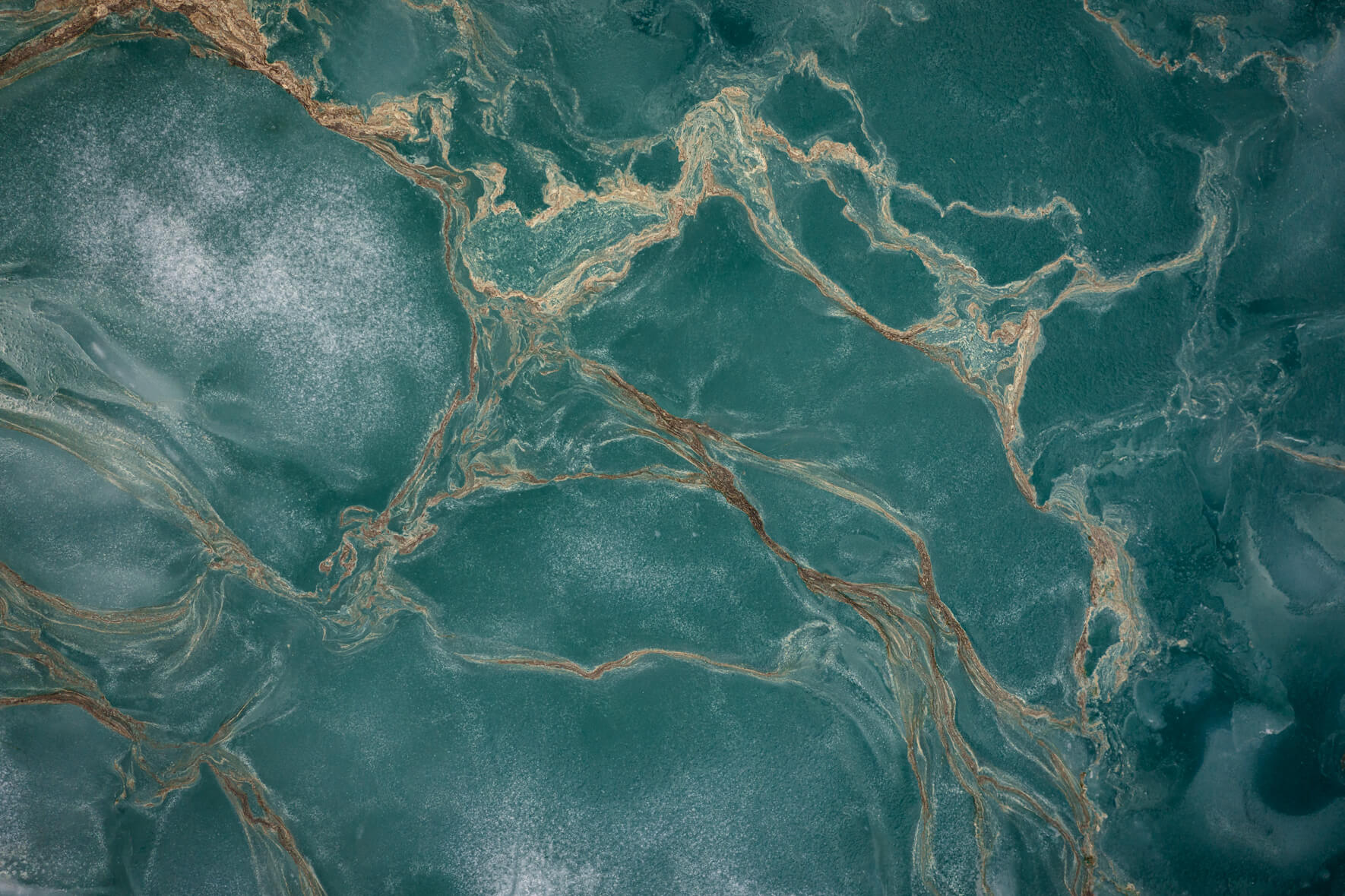 Abstract aerial view of a thawing lake with ice floes and flower pollen forming streaks on the water