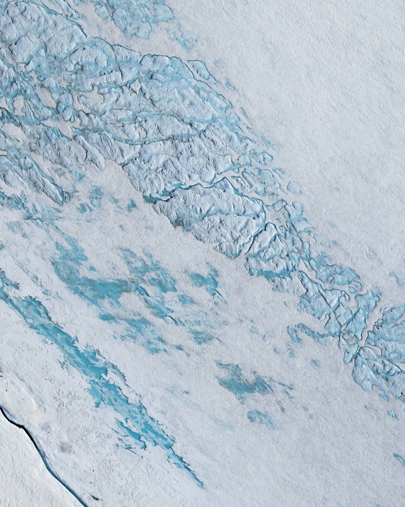 Aerial view of meltwater channels flowing over glacier in Alaska