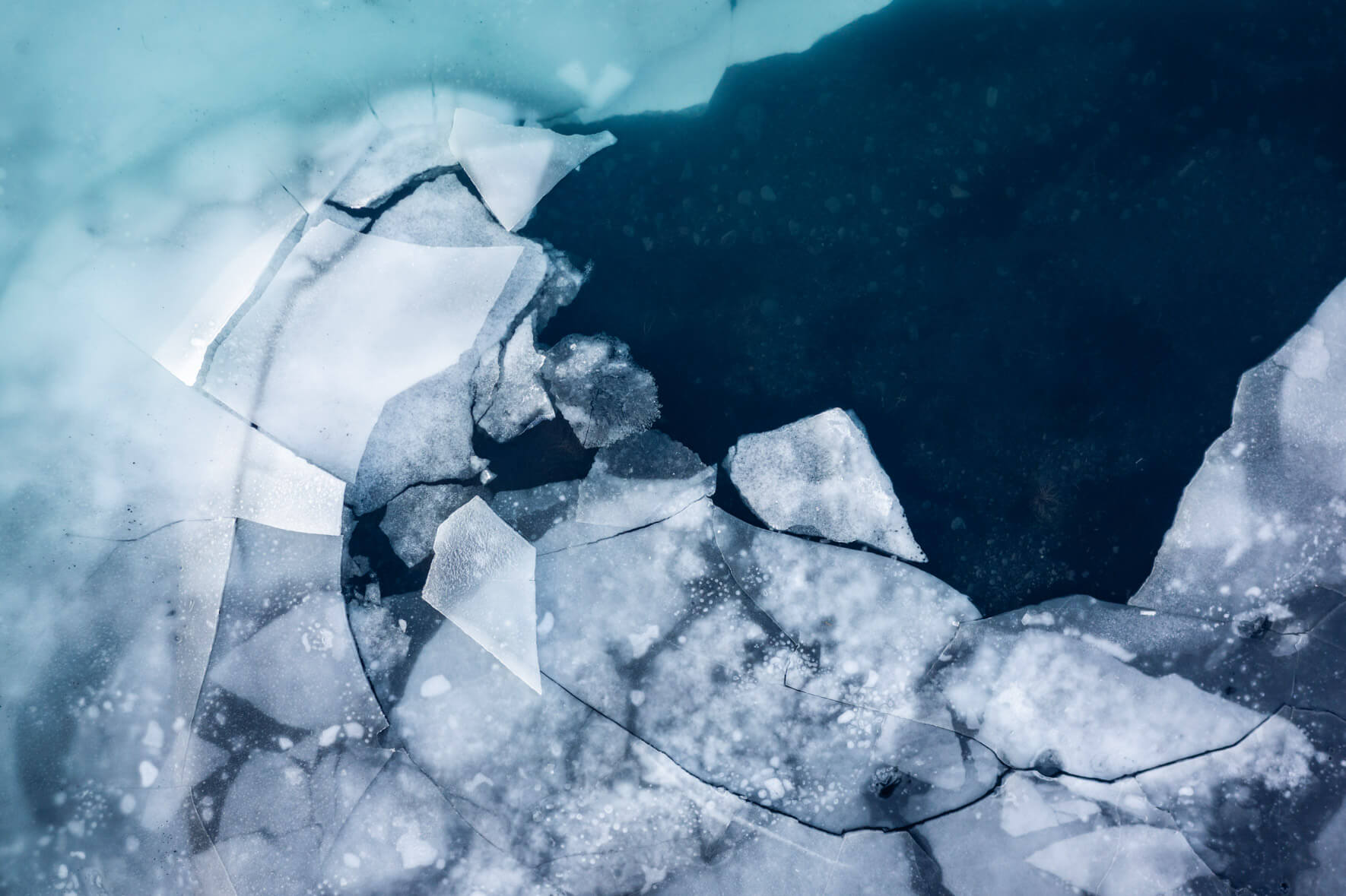 Aerial photography of a thawing lake in Iceland with large ice floes on the surface