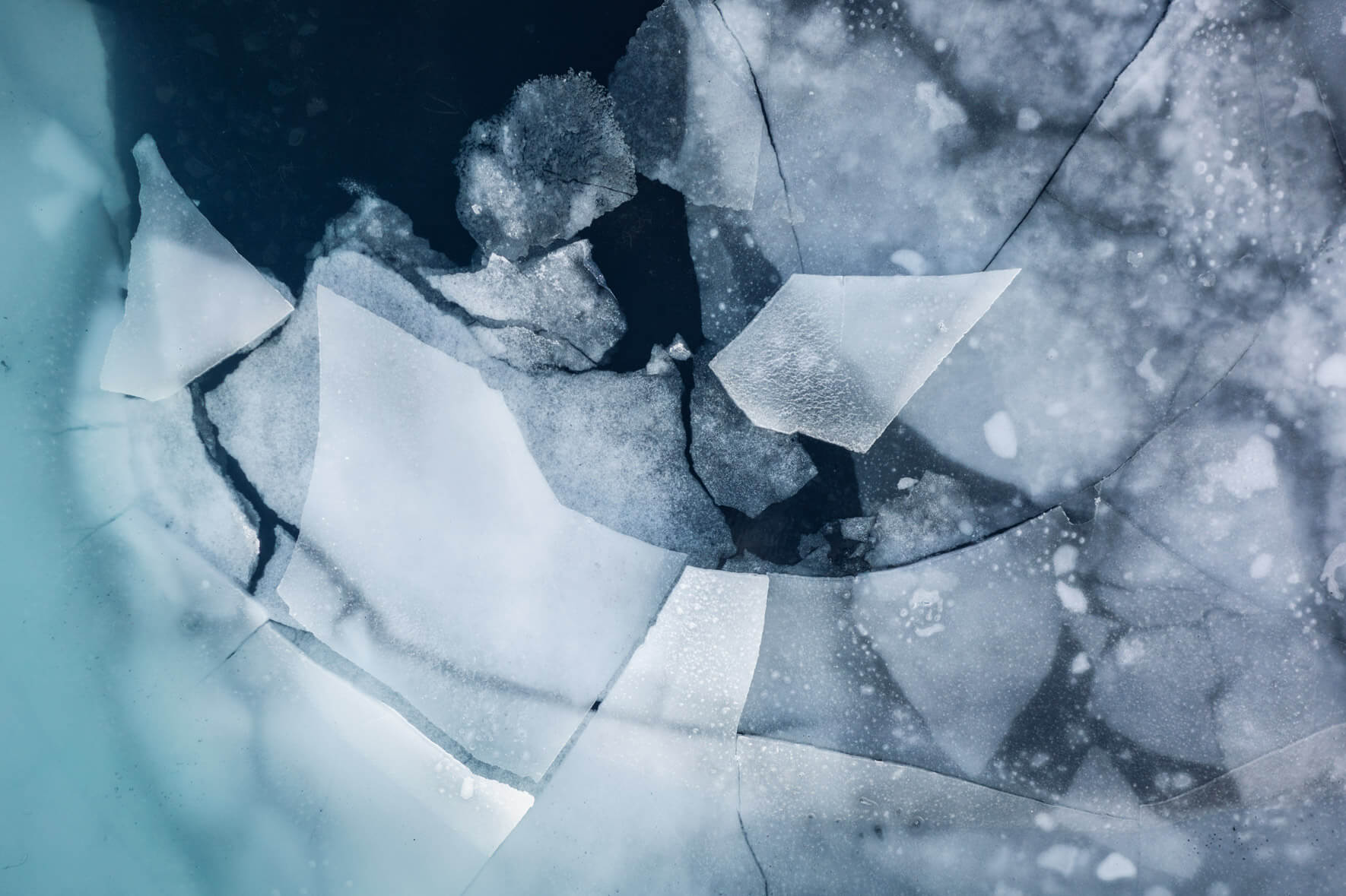 Aerial view of a thawing lake in Iceland with cracked ice floes on the surface