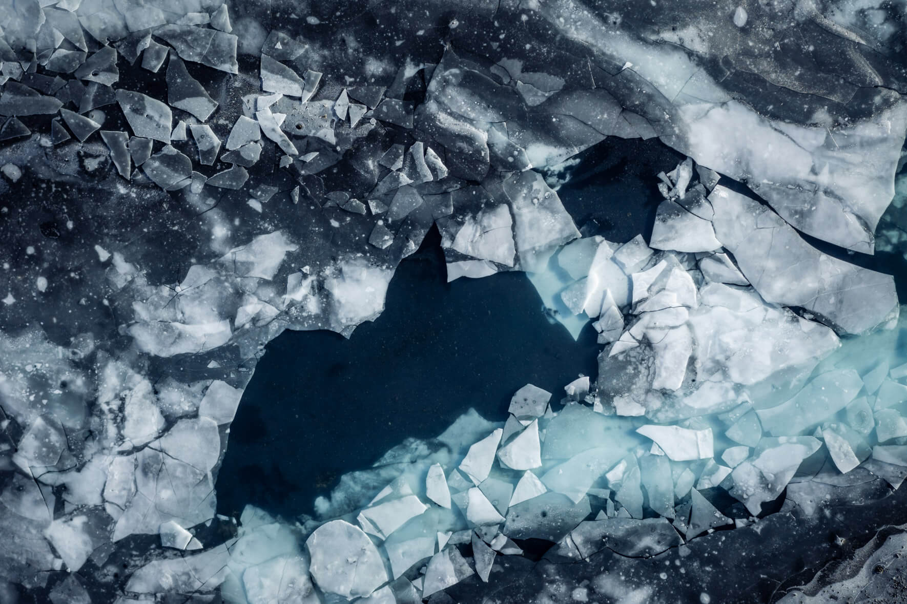 Aerial photography of a thawing lake in Iceland with numerous broken ice floes on the surface