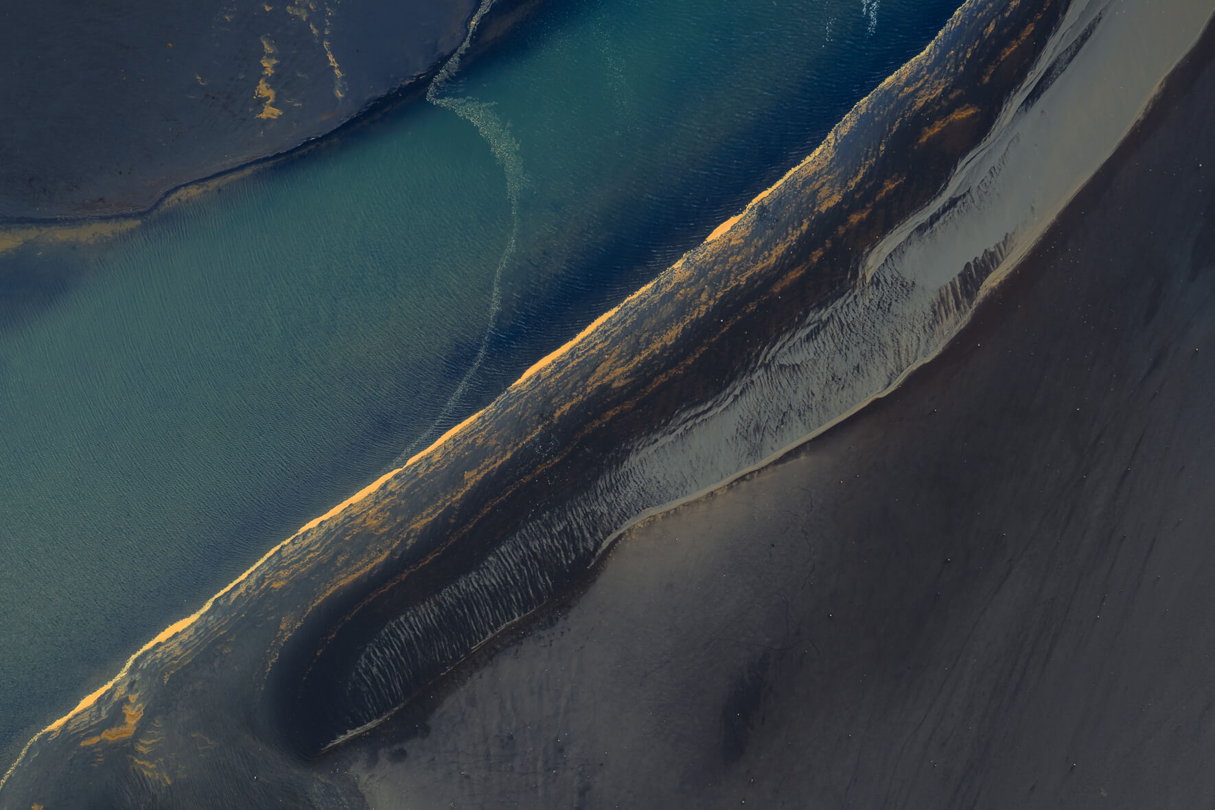 Aerial view of Icelandic coastline showing fine sediment layers and violet reflections on wet sand