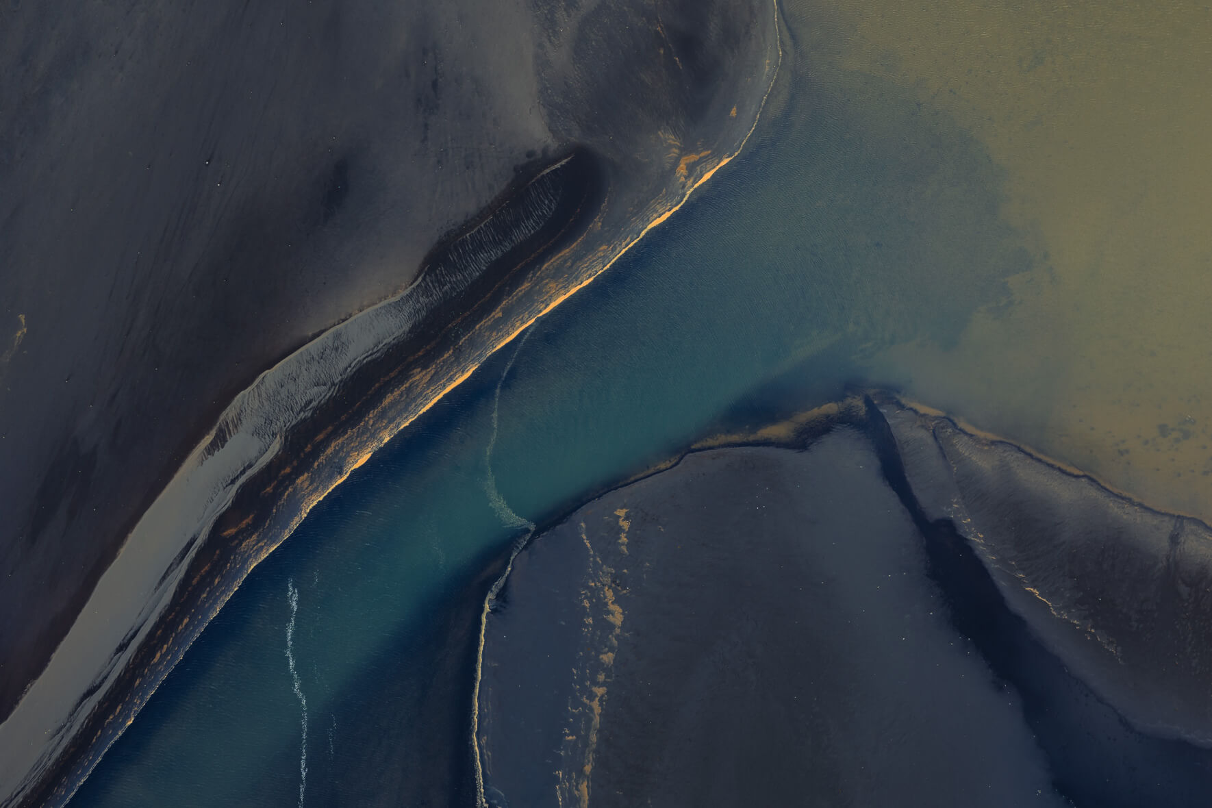 Aerial view of Icelandic coastline showing fine sediment layers and blue river