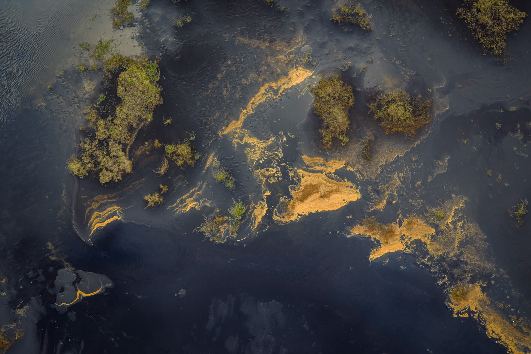 Aerial abstract of Icelandic lagoon blending blue tones, fine foam lines, and dark reflections