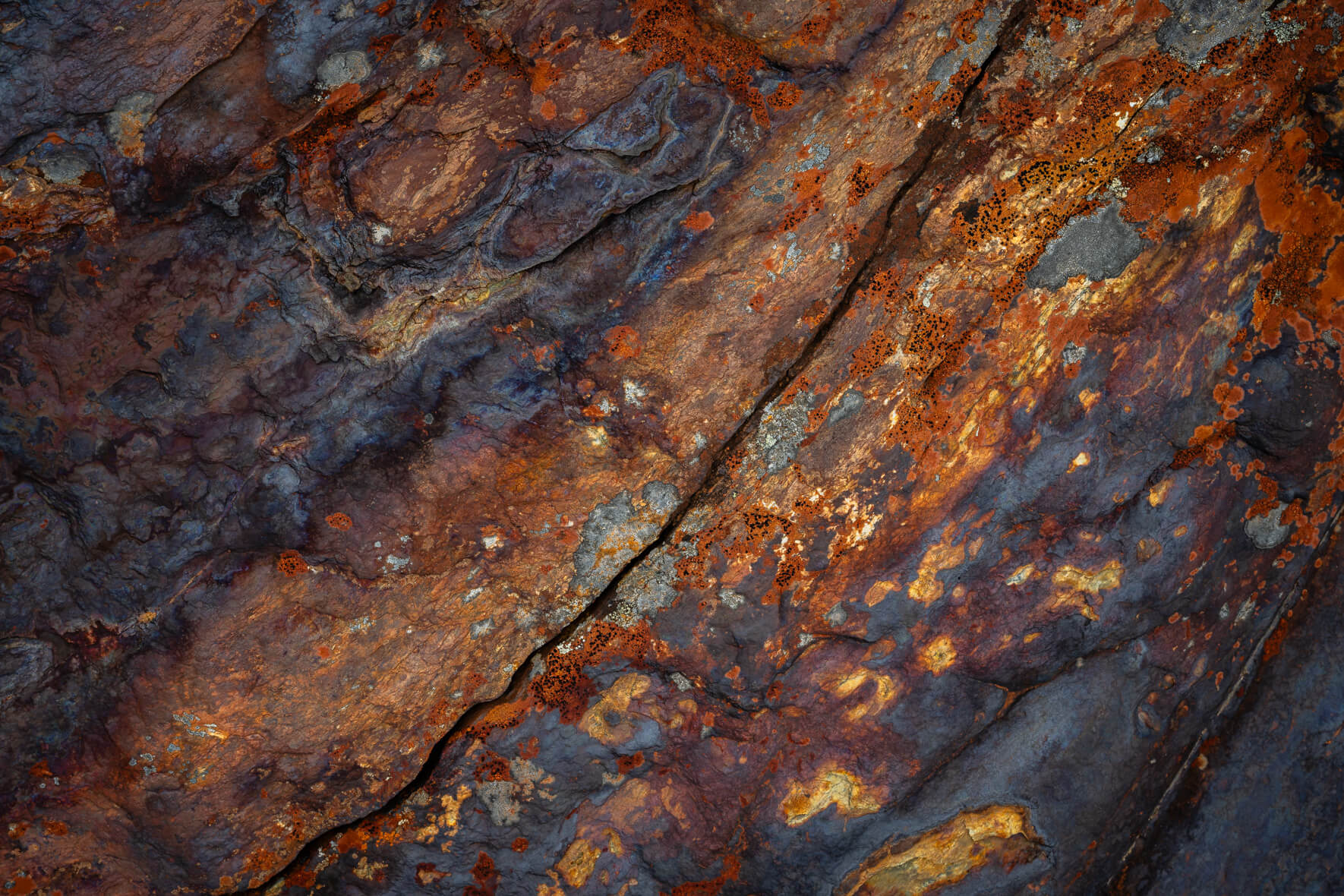 Oxidized stone surface with deep orange and blue mineral contrasts