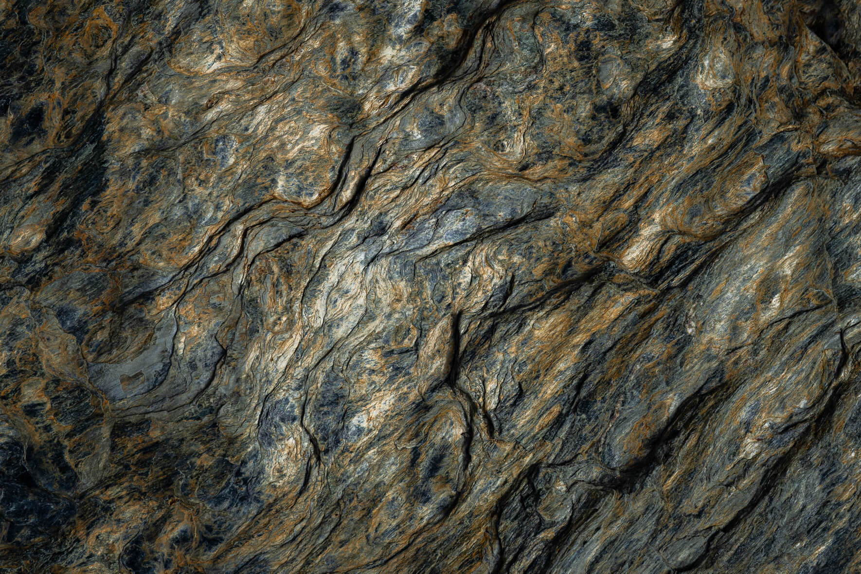 Foliated rock structure with golden highlights and fine gray textures