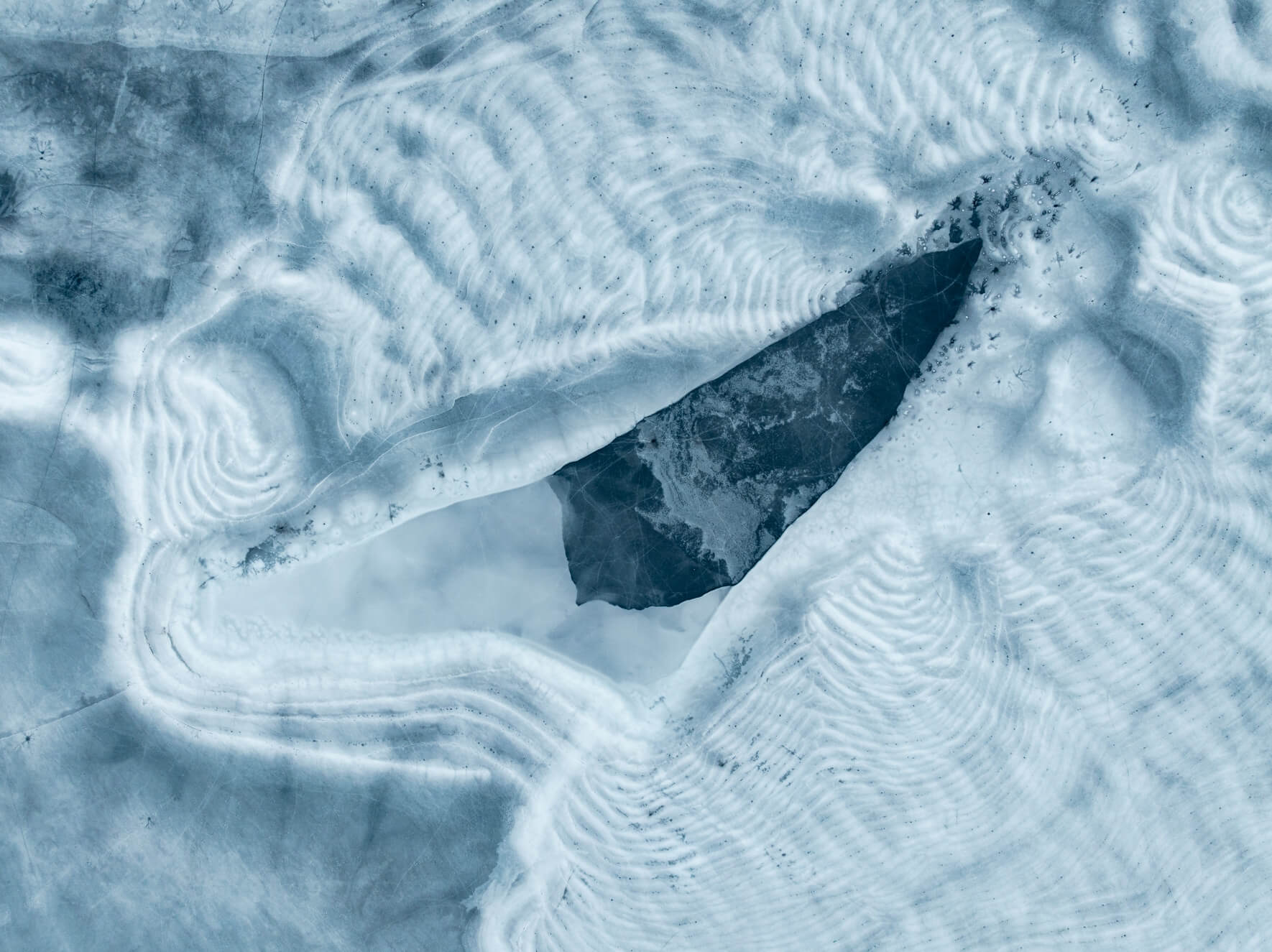 Aerial view of fractured frozen lake surface with geometric ice shapes