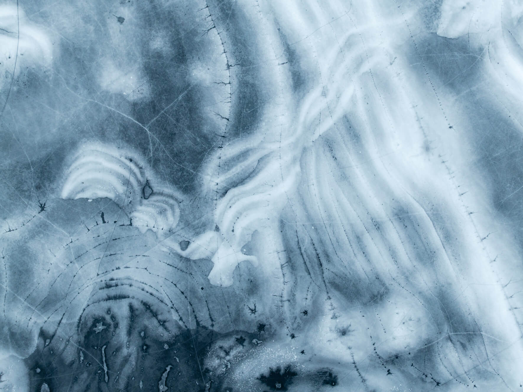 Aerial view of frozen lake with intersecting snow and ice layers