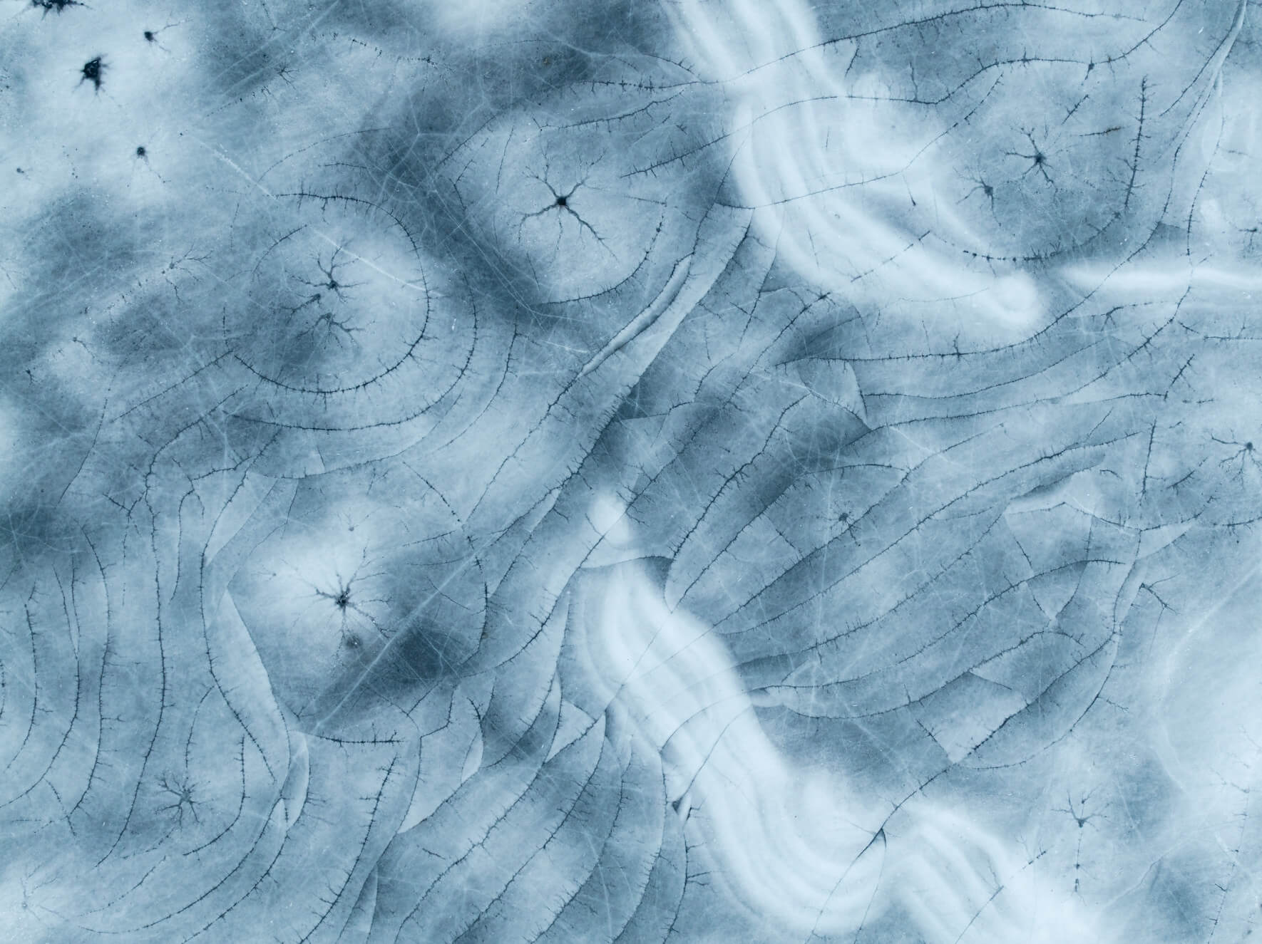 Cracked winter ice forming winding structures across the frozen surface