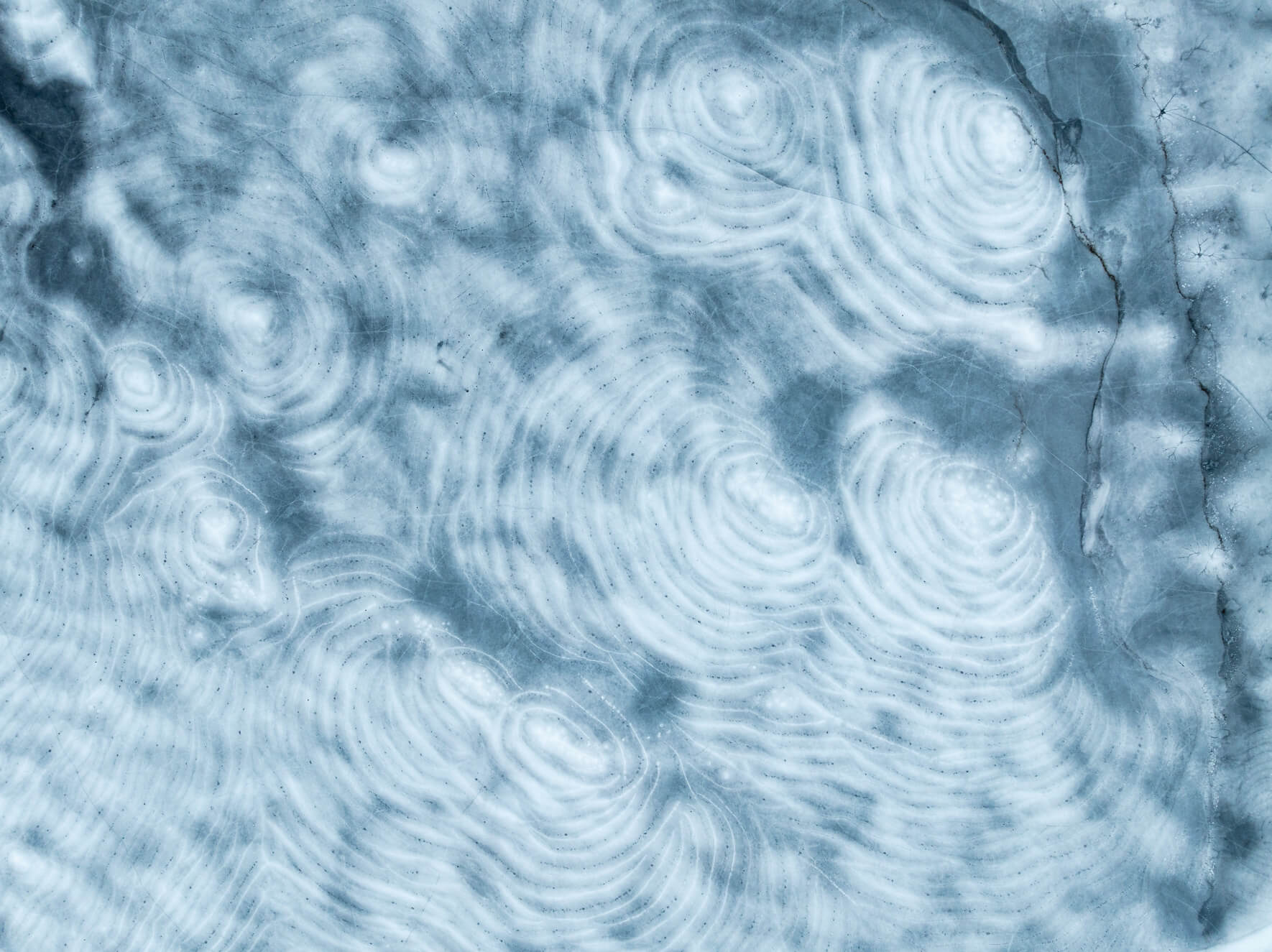 Aerial view of frozen lake with circular patterns of snow