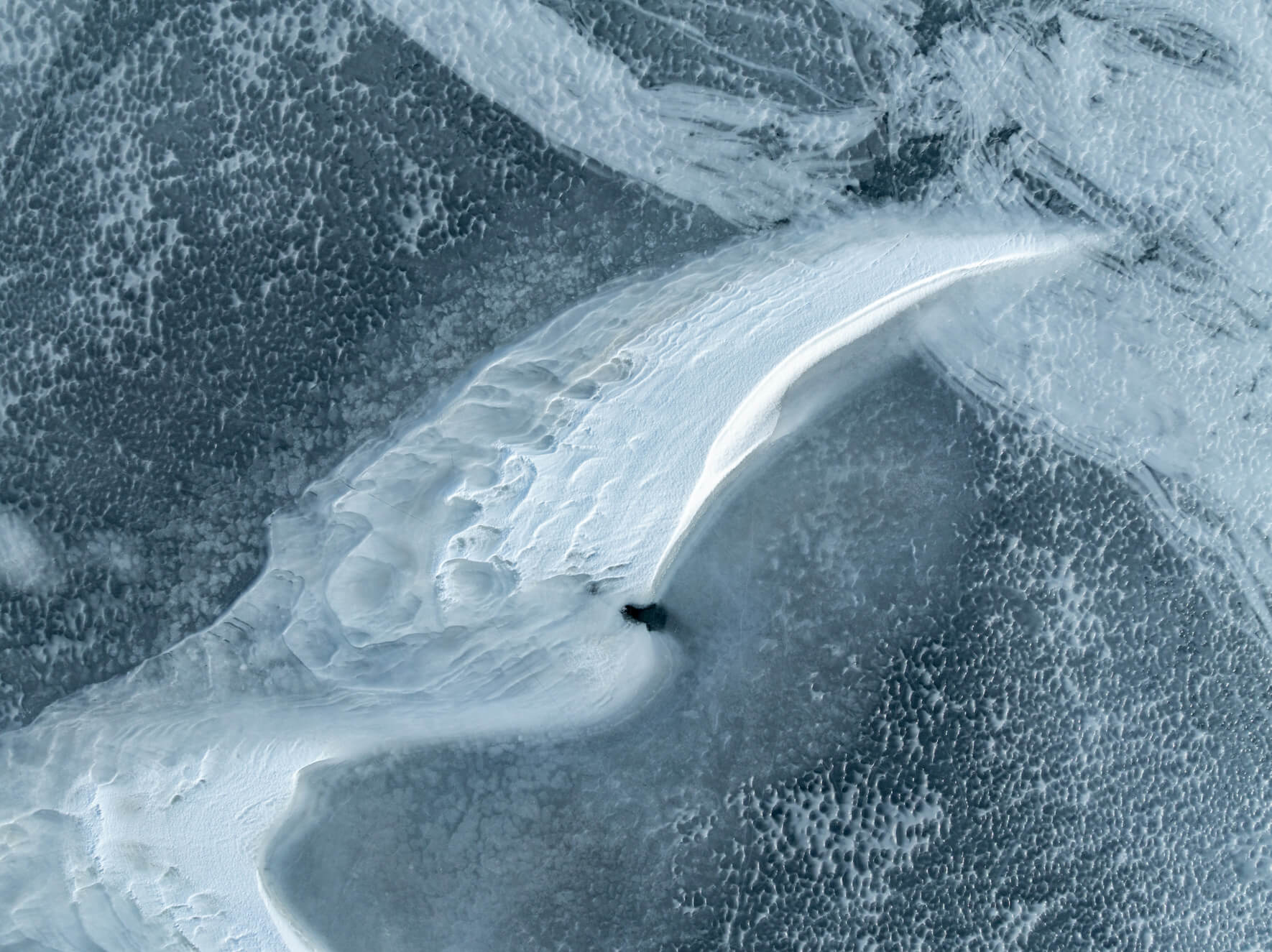 Aerial perspective of thawing ice showing textured snow ridges