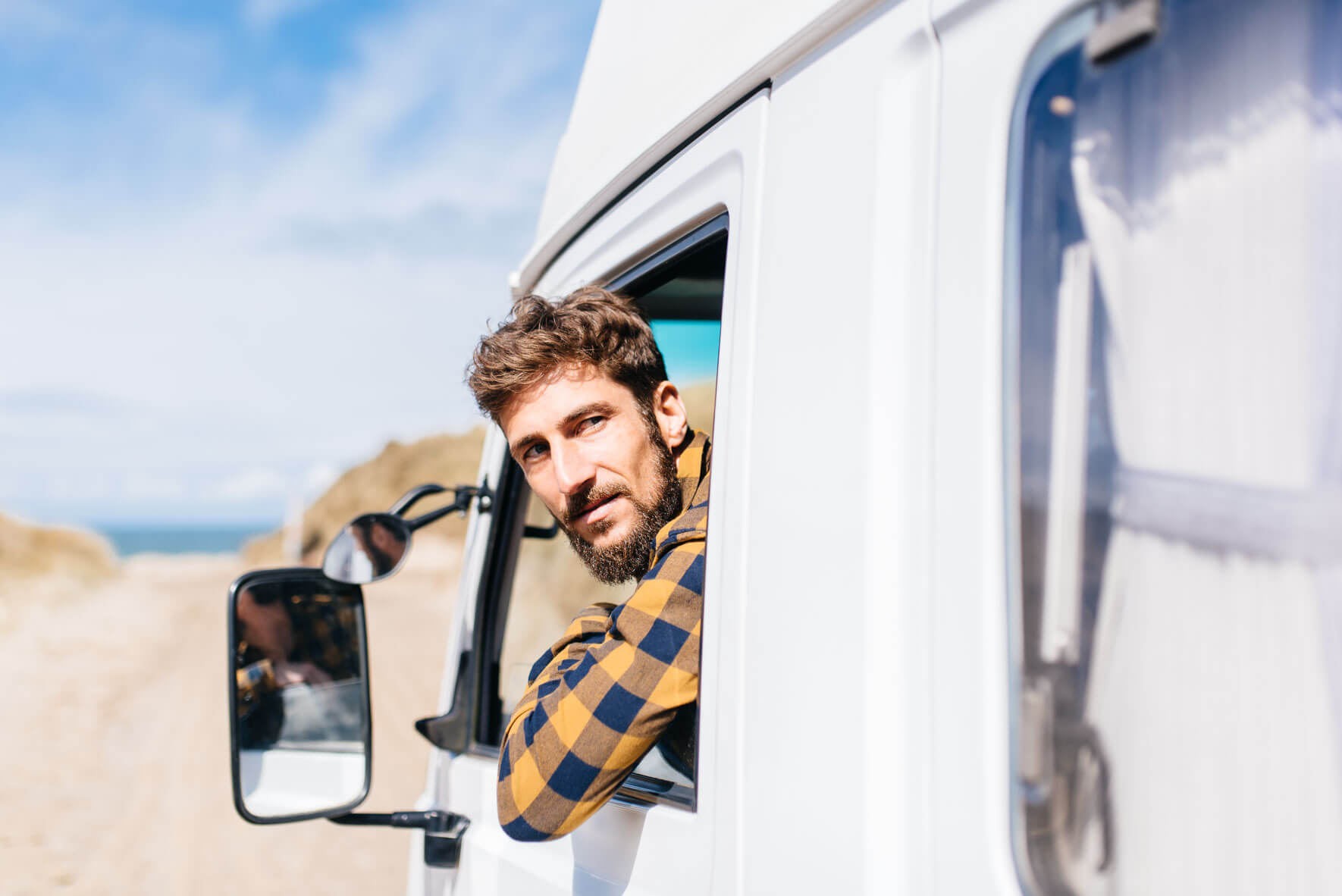 Man driving backwards on the beach in a camper van