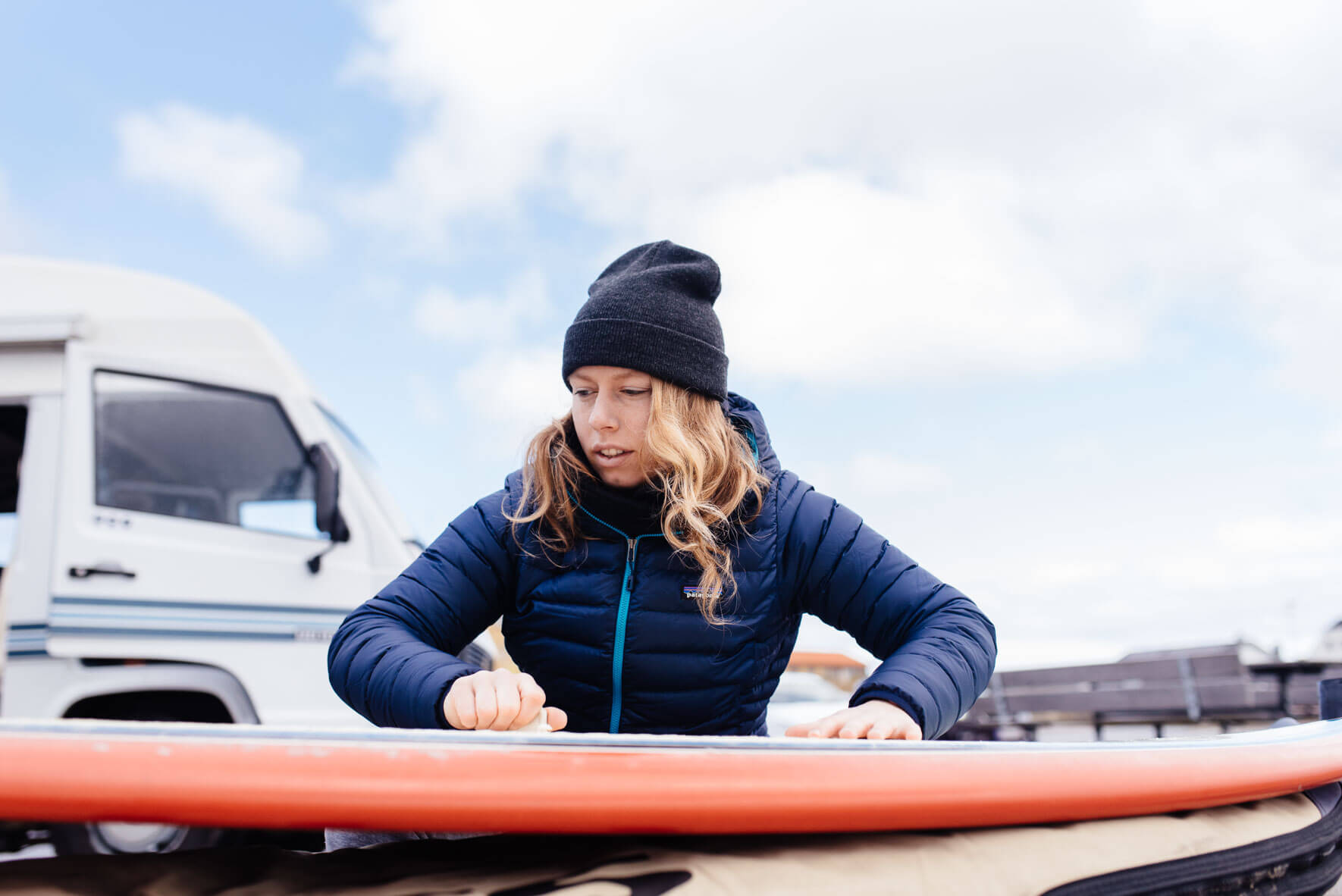 Woman getting surfboard ready on Klitmøller beach in Denmark