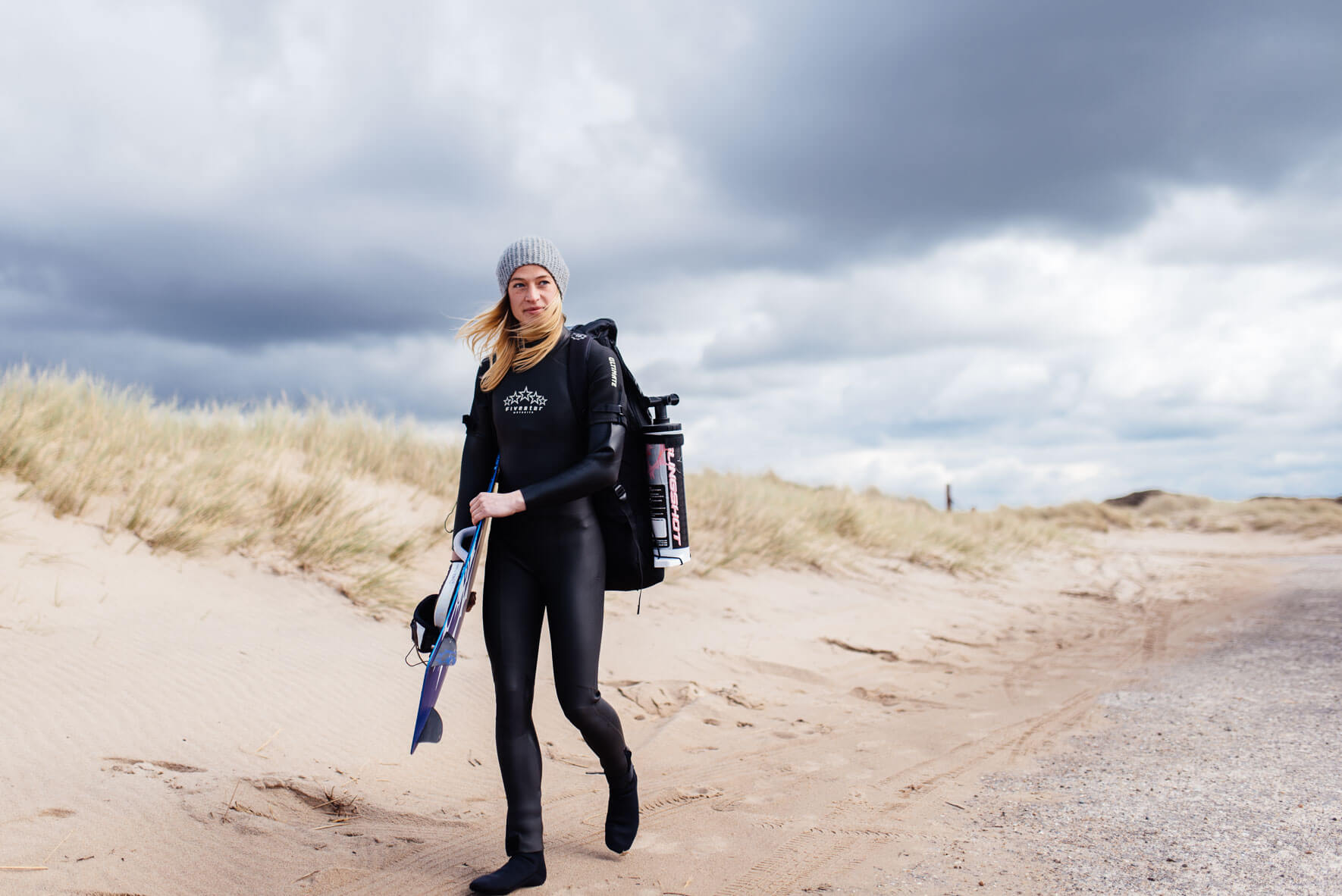Woman with kite equipment walking on the beach