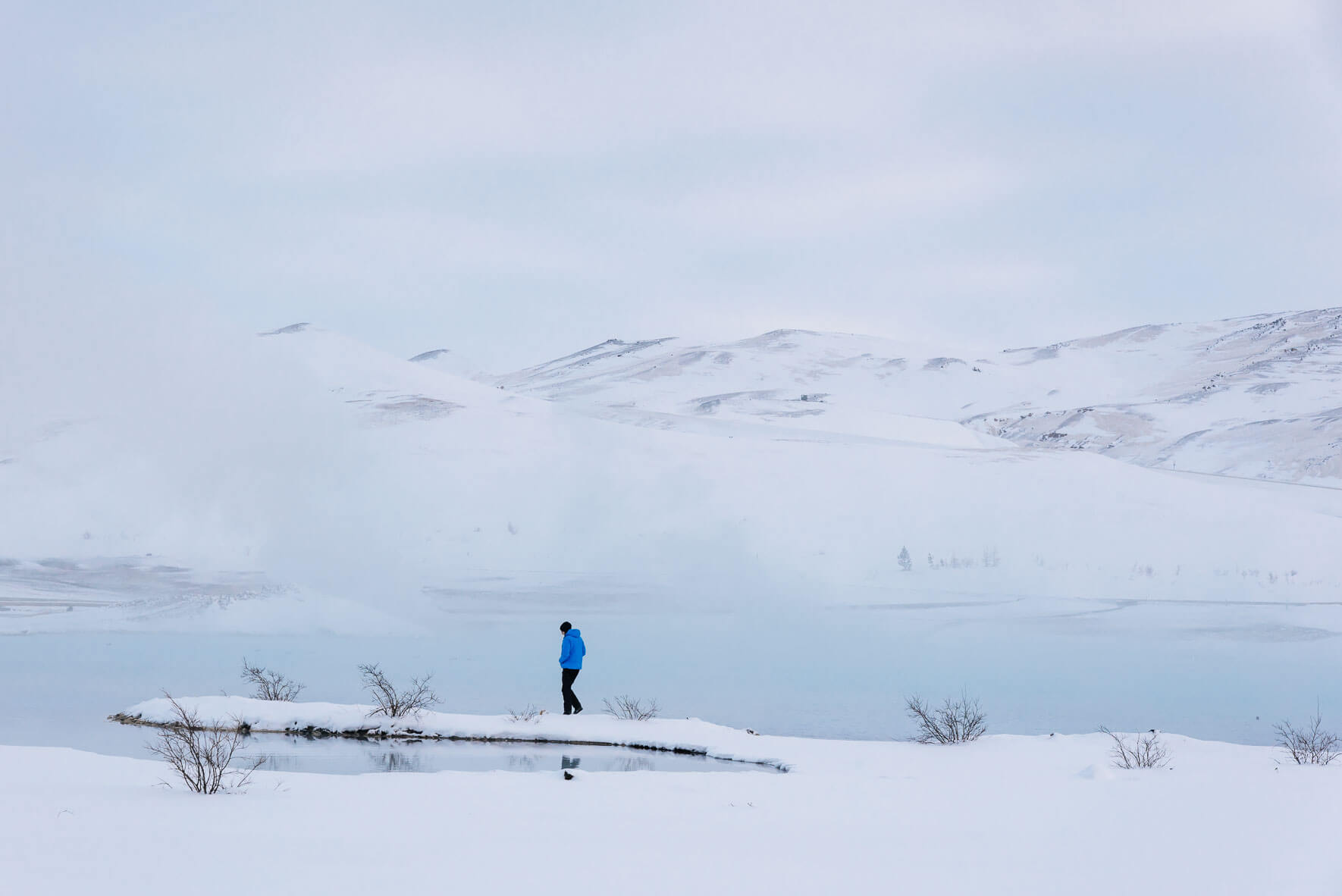 Man walking near geothermal lake in Mývatn, Iceland