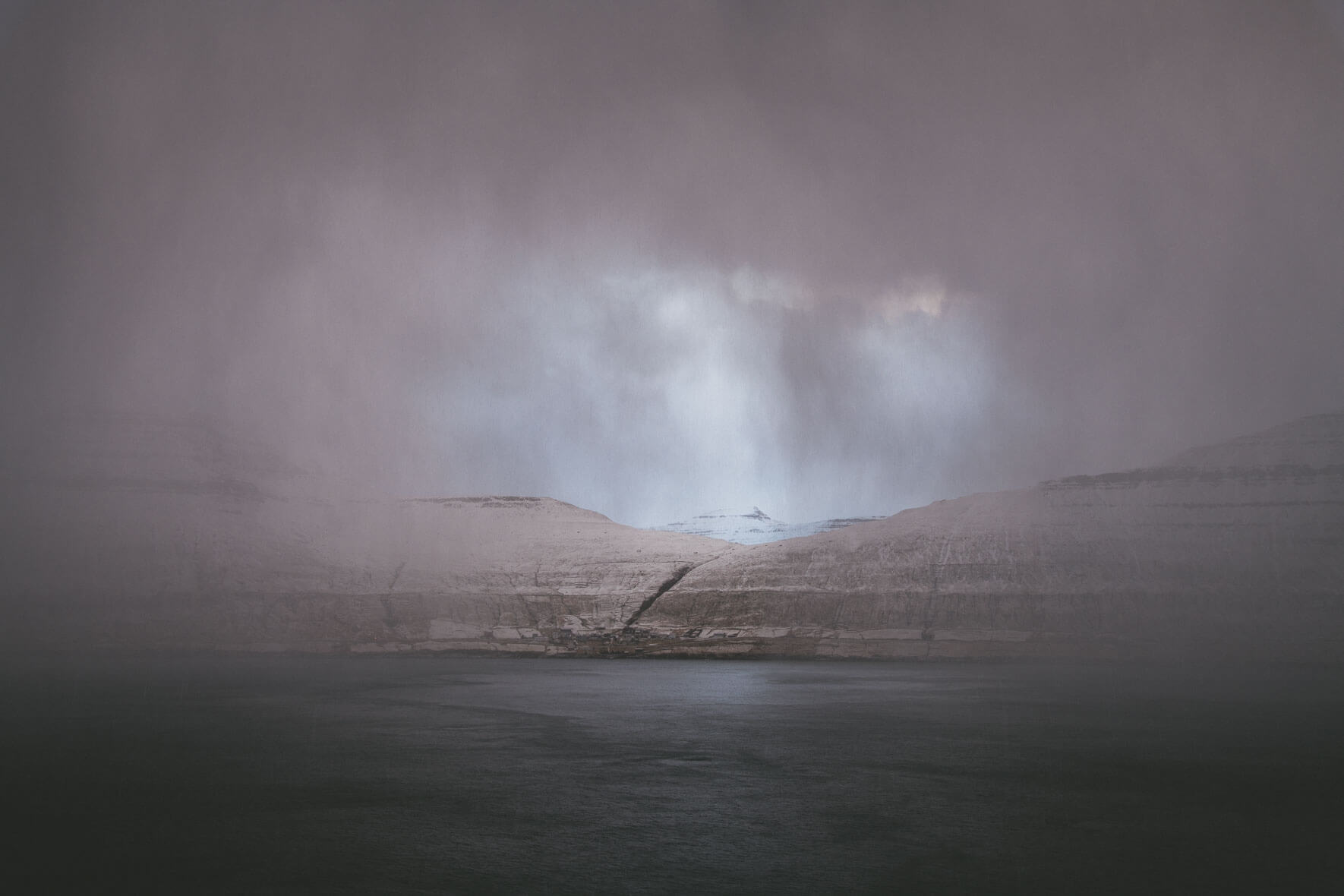The island Kalsoy on the Faroe Islands between dark winter clouds