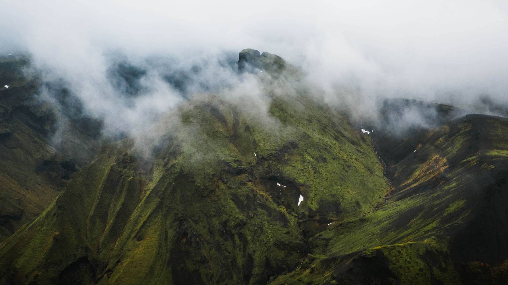Green mountain in the clouds in the Highlands of Iceland