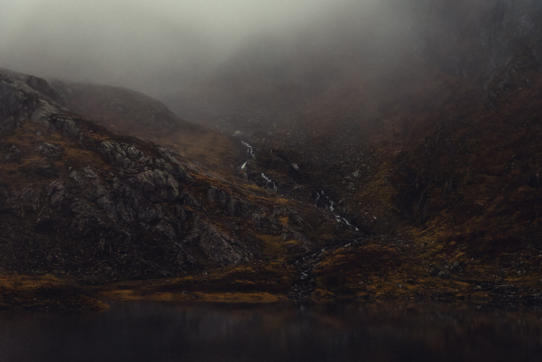 Waterfall in dark and foggy mountain scene